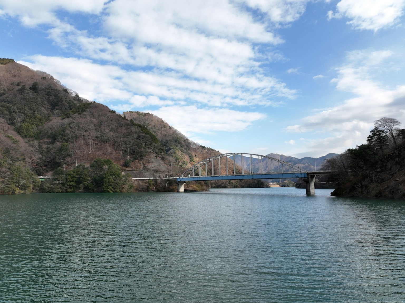 Vista escénica de un puente sobre agua tranquila rodeada de montañas