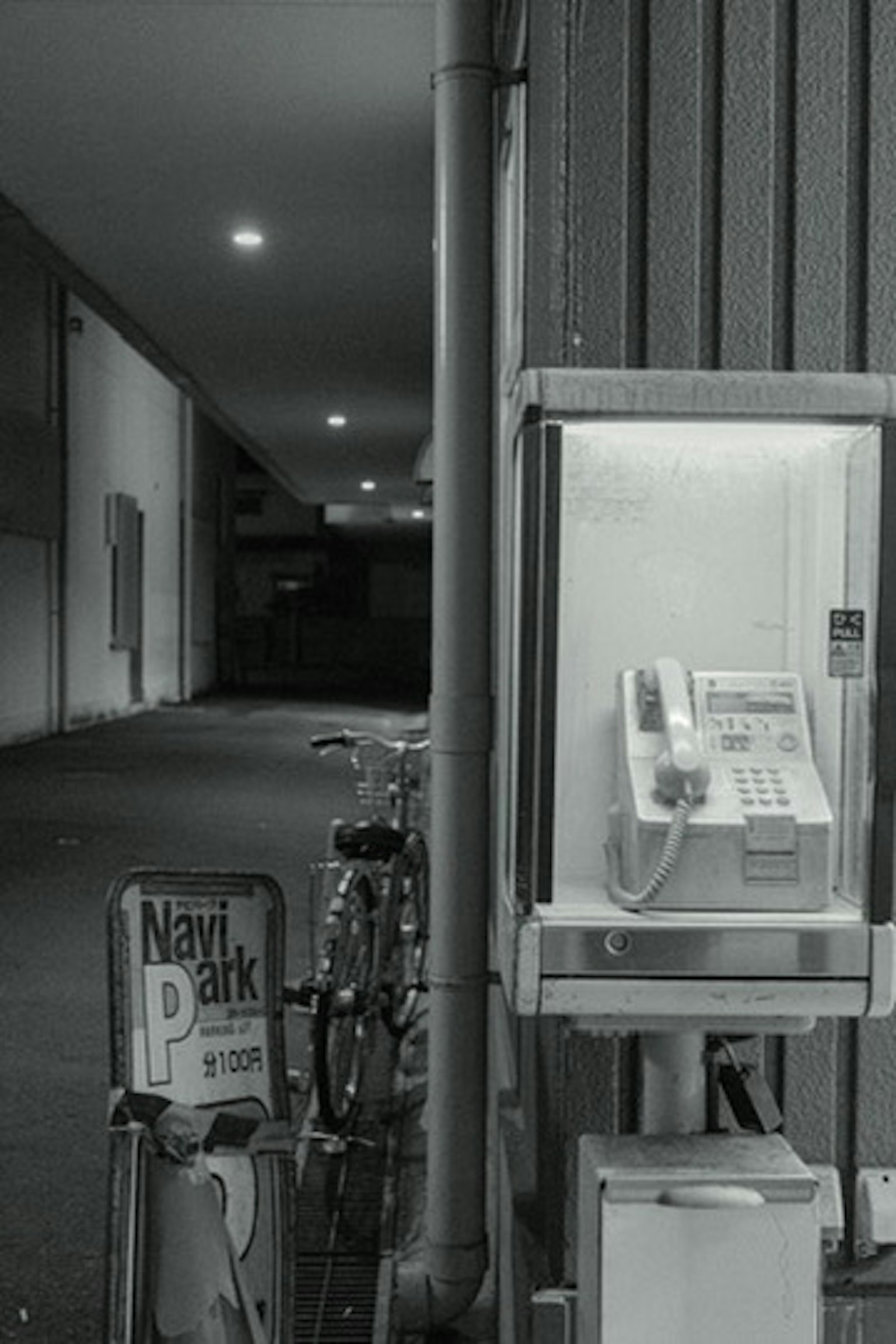 Image d'une cabine téléphonique et d'un vélo dans une ruelle sombre
