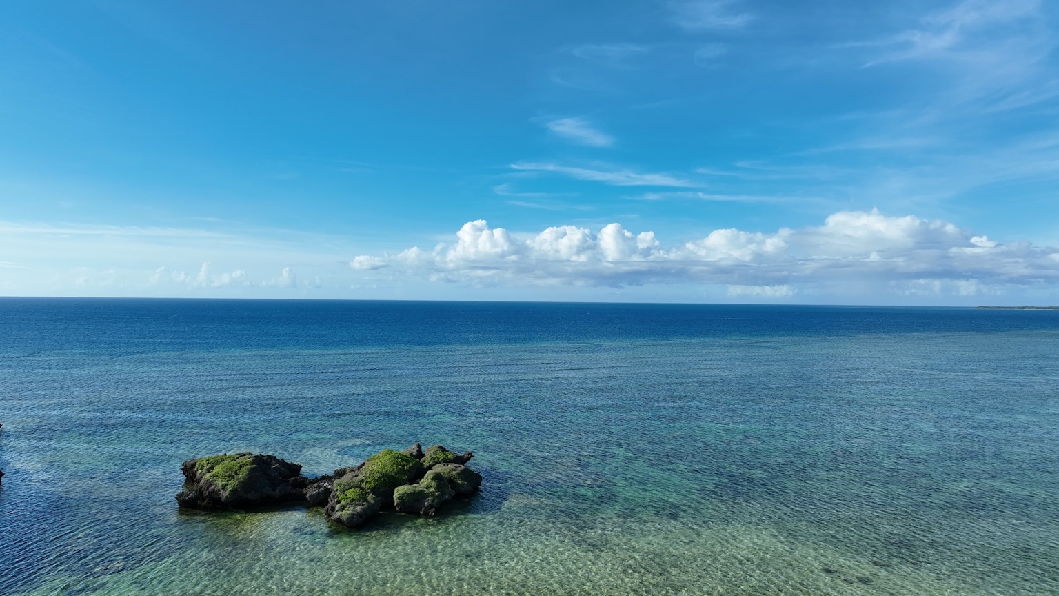 Rock formations in a clear blue ocean under a bright sky