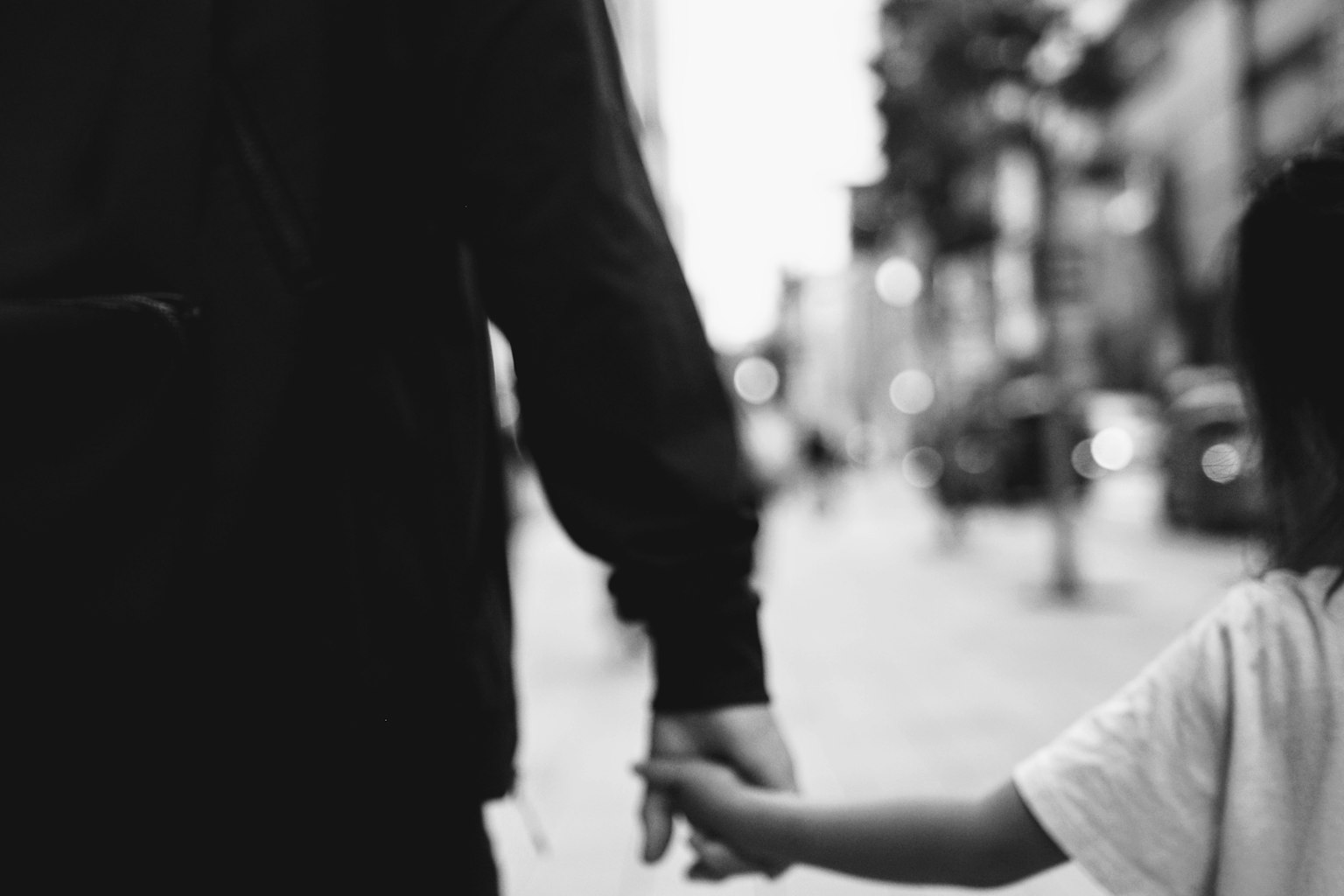 Silhouette in bianco e nero di un genitore e un bambino che si tengono per mano