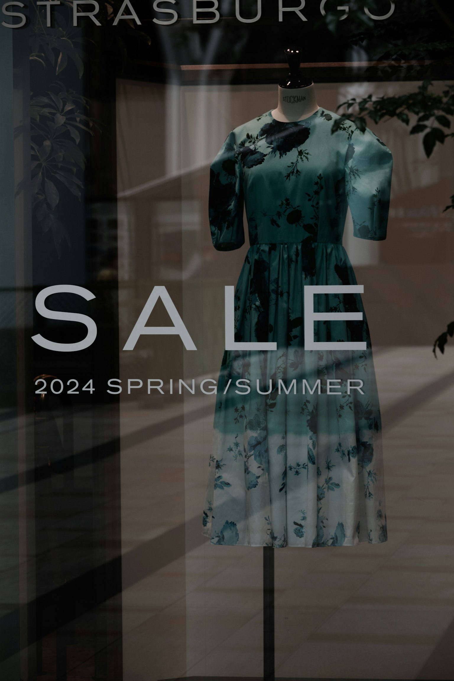 Schaufenster mit blauem Blumenkleid Verkaufsschild und Kollektion Frühling/Sommer 2024