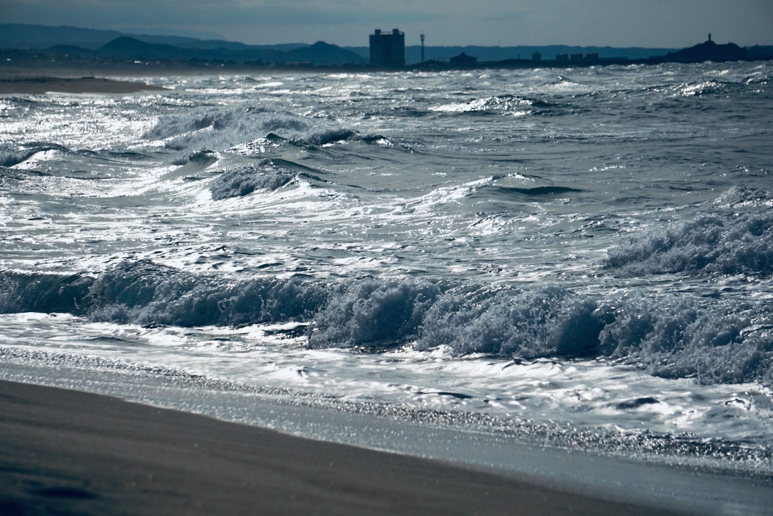 波濤洶湧的海浪與遠處建築的海岸線