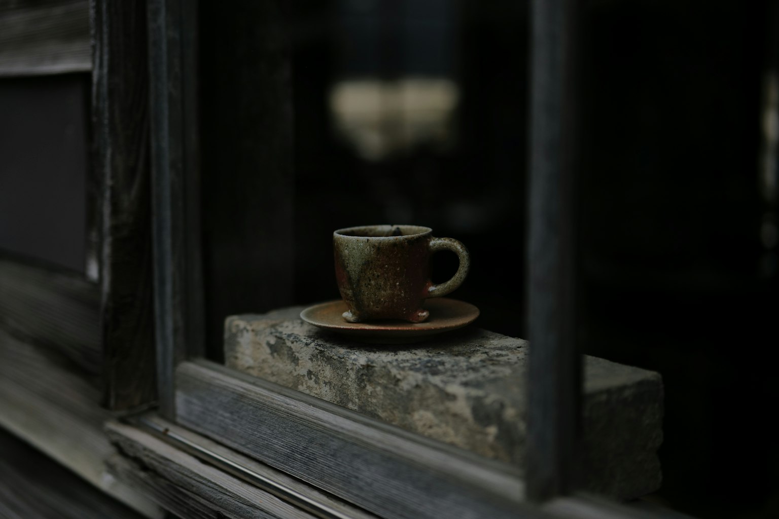 Eine ruhige Szene mit einer braunen Tasse und Untertasse, die durch ein Fenster gesehen wird