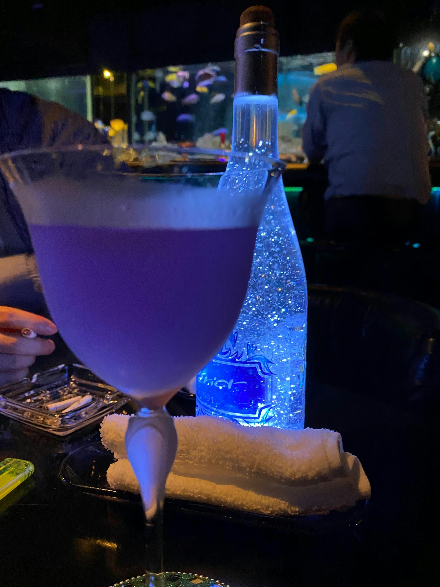 酒吧环境中的紫色鸡尾酒和发光瓶子