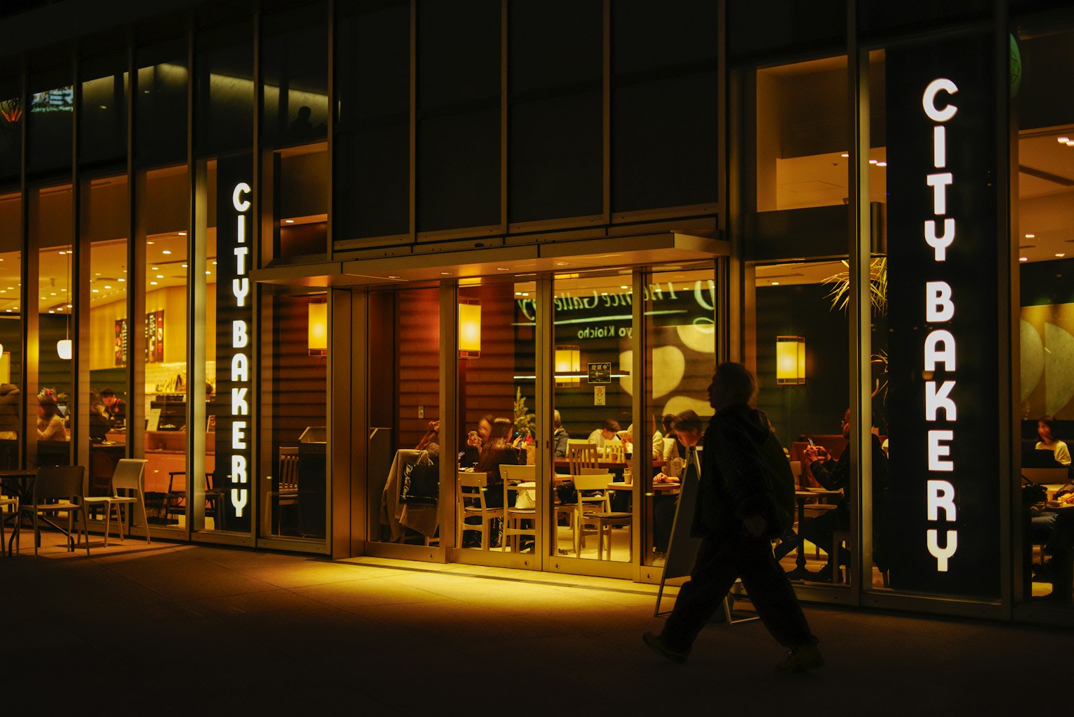Exterior of City Bakery at night with diners inside