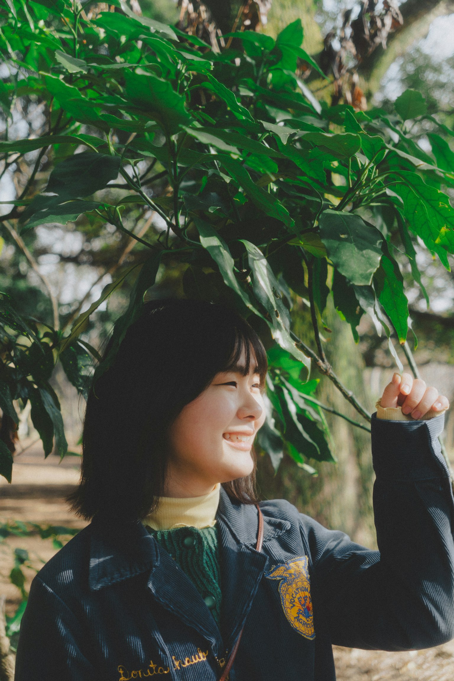 Woman smiling under green leaves
