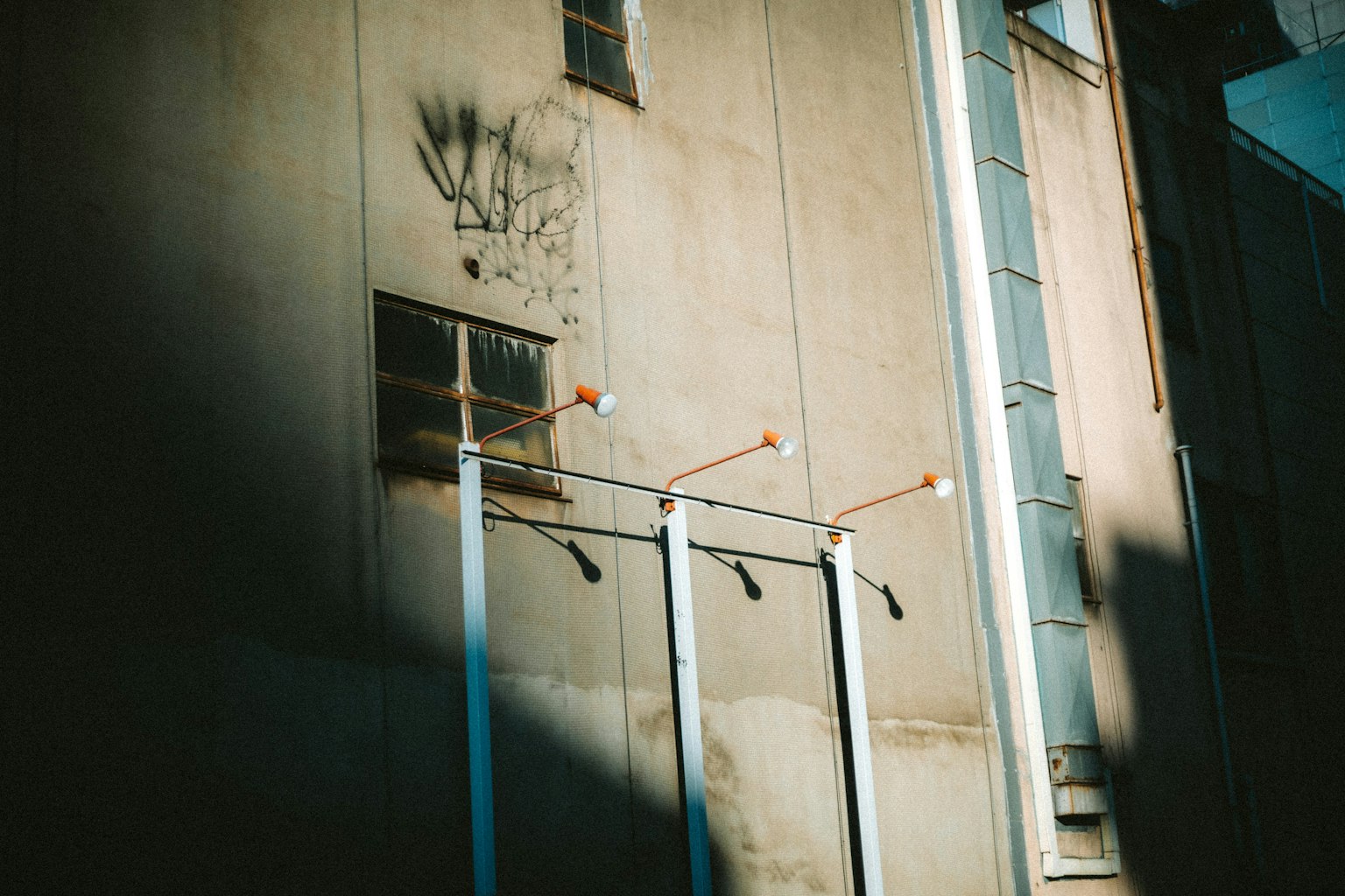 White pipes standing against an industrial wall with shadows