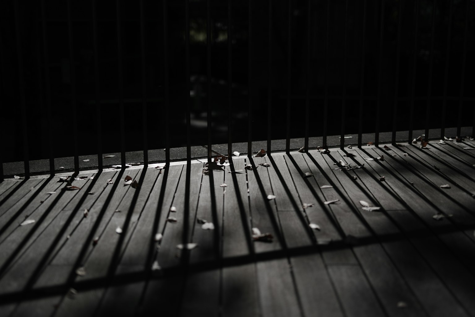 Szene mit einem Holzdeck und den Schatten eines Zauns in einer dunklen Umgebung
