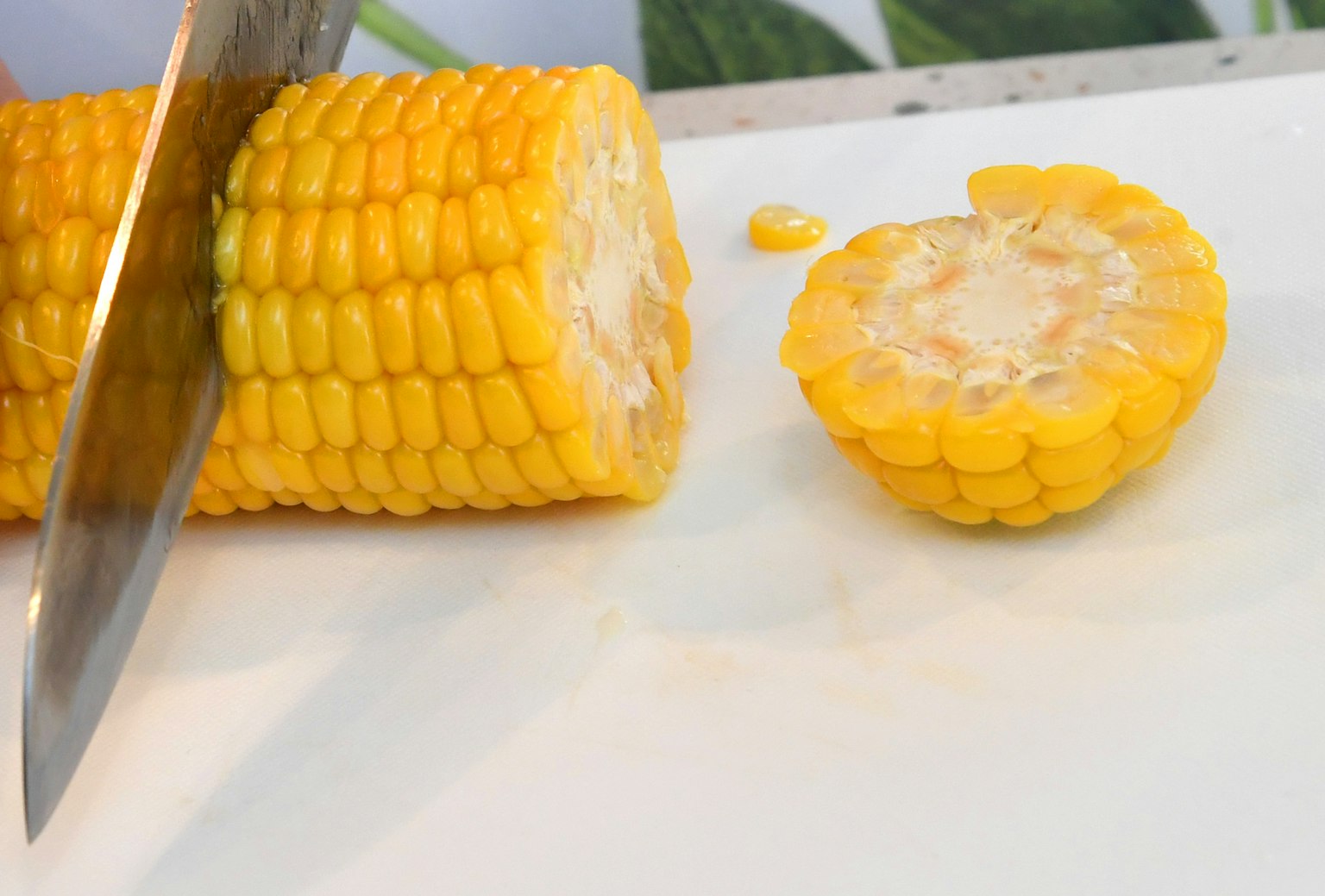 Una pannocchia di mais gialla che viene affettata con un coltello mostrando la superficie tagliata
