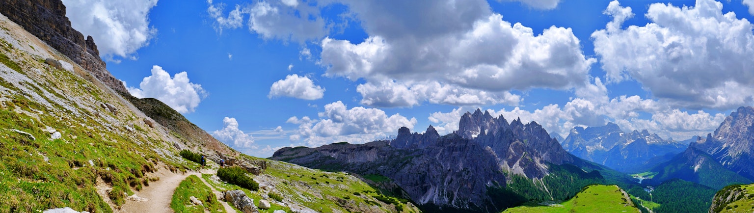 Panoramablick auf Berge und blauen Himmel mit einer grünen Wiese und einem Weg