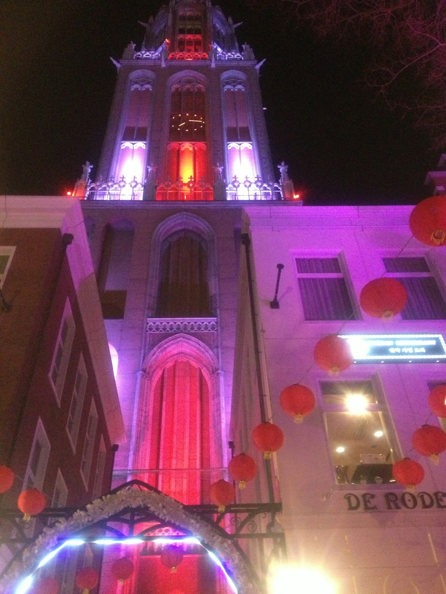 Torre illuminata in rosso e viola con lanterne rosse di notte