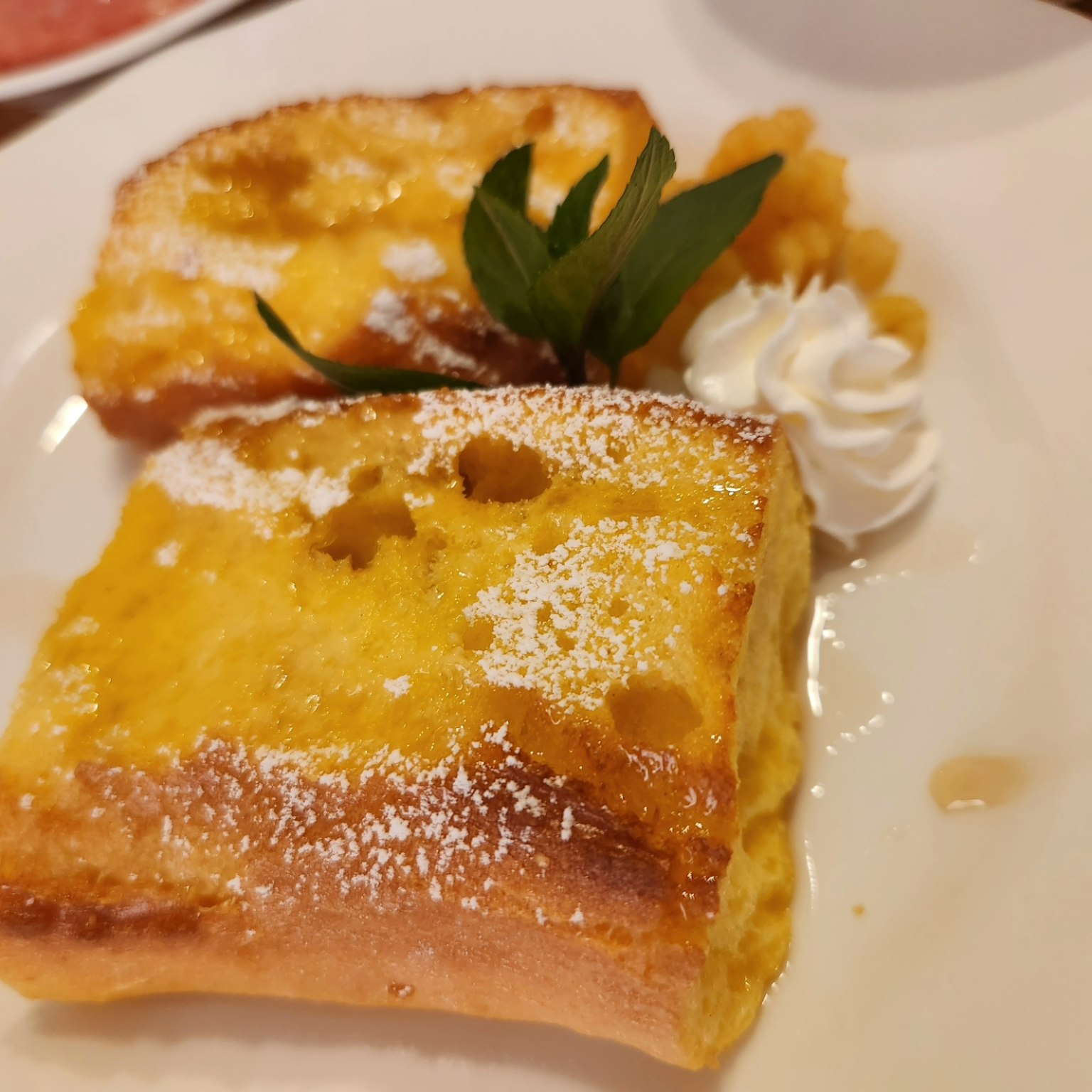 Deliciosas rebanadas de tostada francesa cubiertas con azúcar en polvo y crema