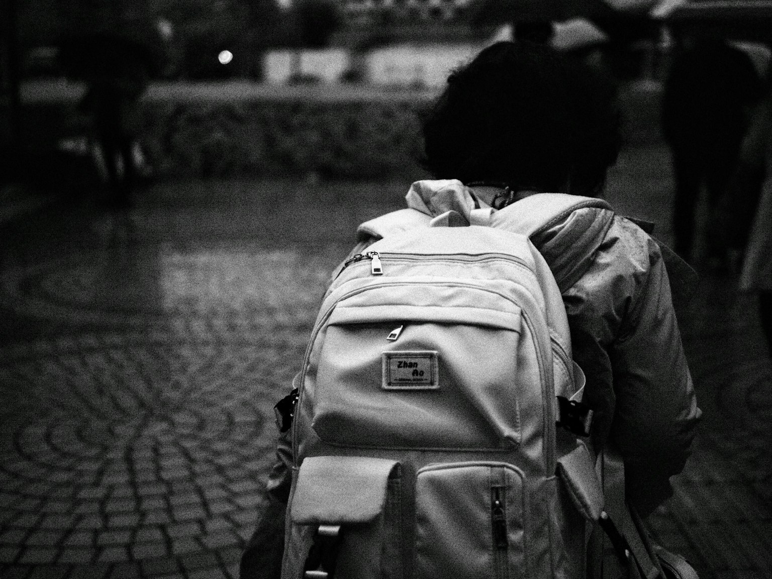 Person geht auf Kopfsteinpflaster mit weißem Rucksack