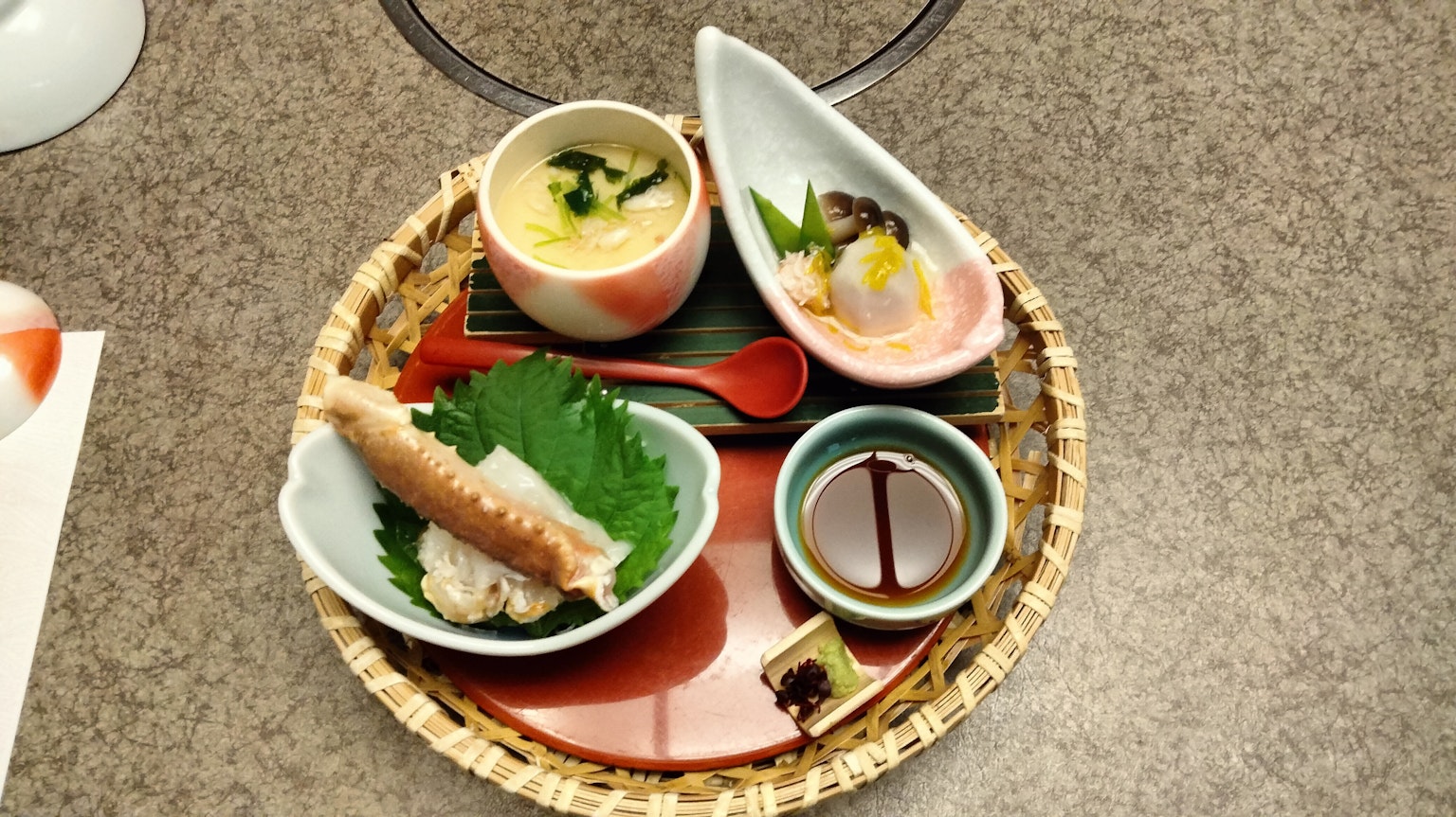 Cucina giapponese splendidamente disposta con foglie verdi uovo al vapore e sashimi in piccoli piatti