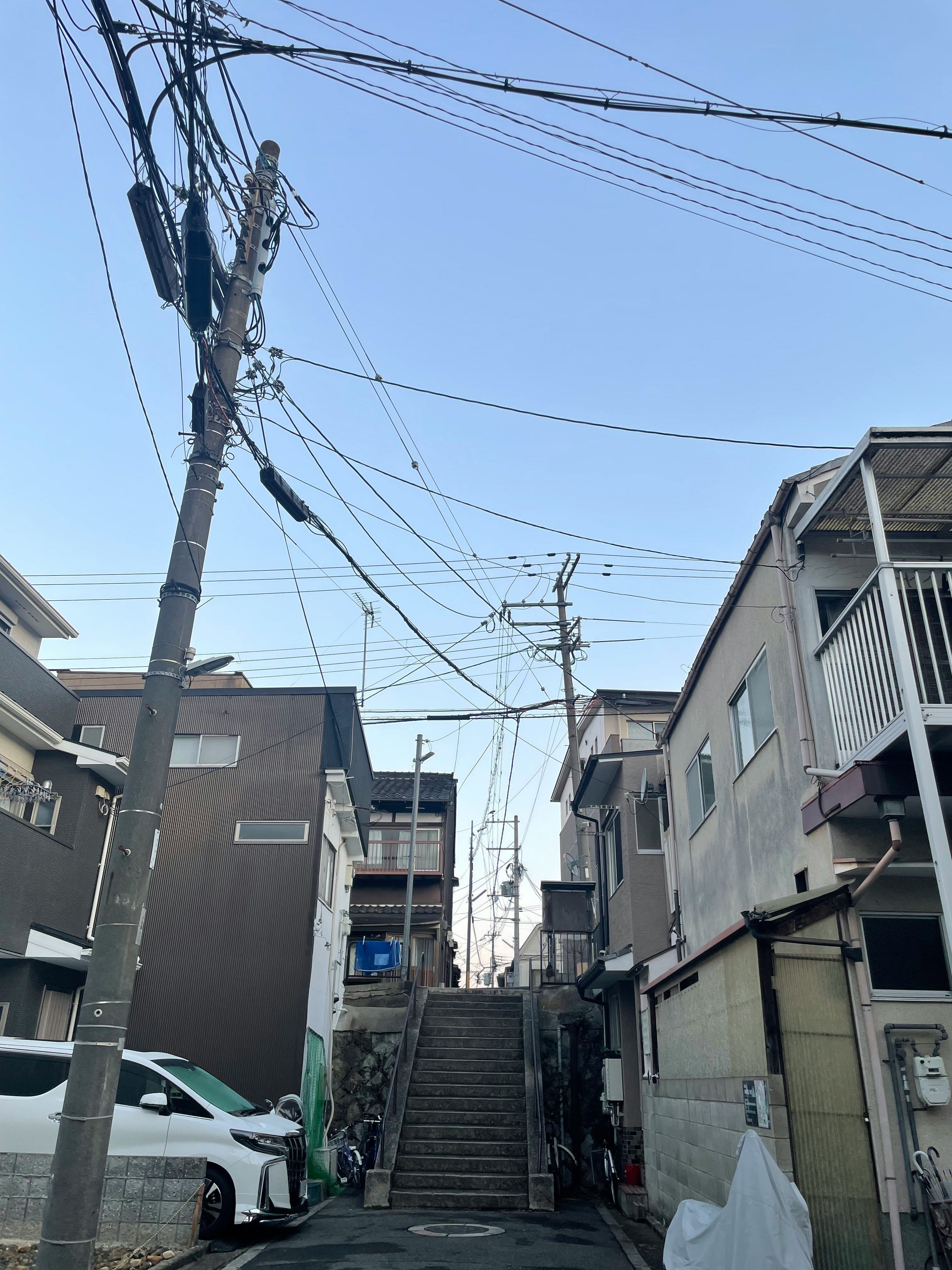 住宅小巷坡道，電線桿與架空電線延伸