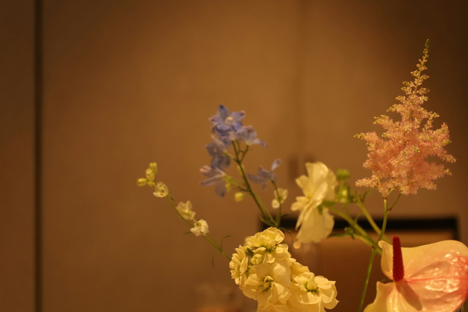 Un bouquet di fiori dai colori tenui con delphinium blu e rose bianche