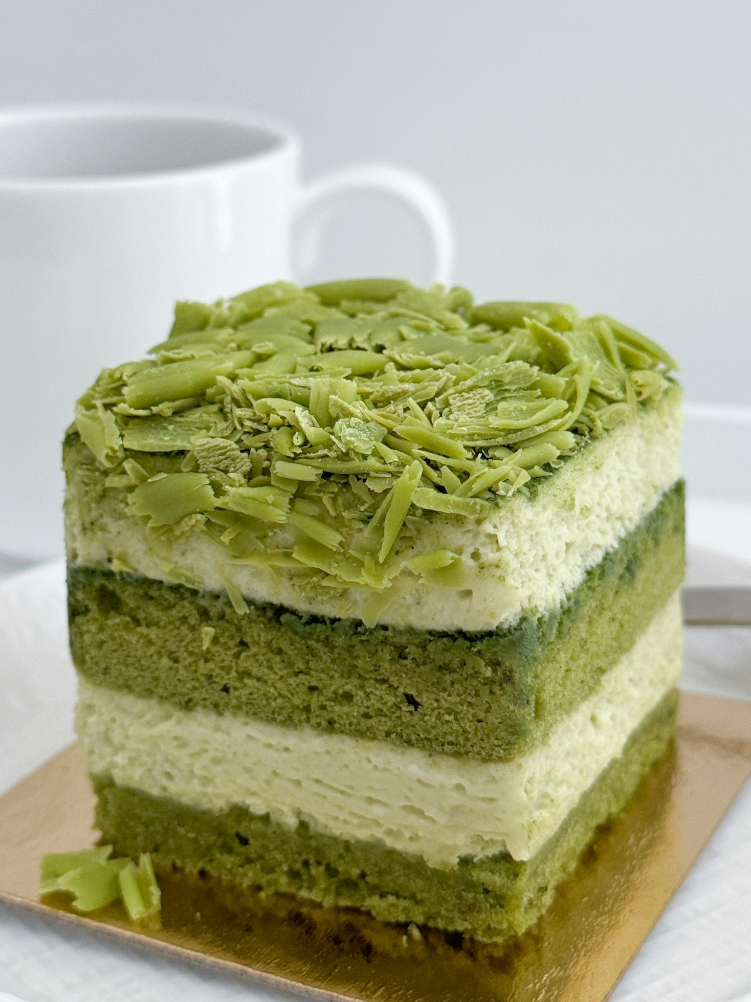 Gâteau en couches au matcha avec garniture de thé vert et tasse blanche