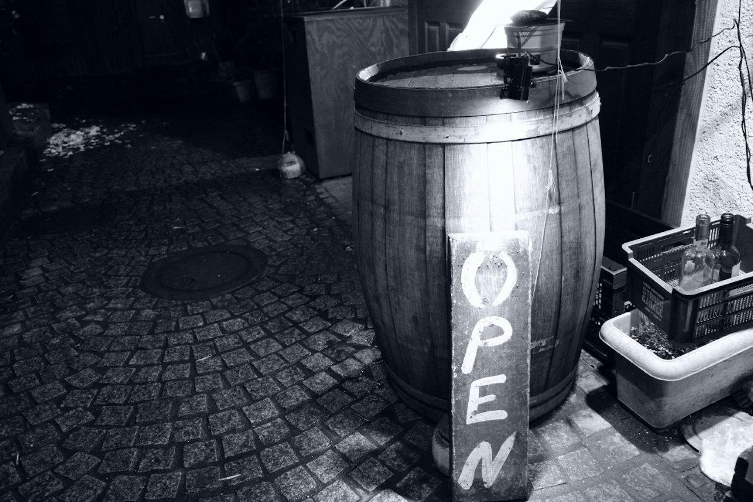 ถังไม้ที่มีป้าย 'OPEN' ในตรอกตอนกลางคืน