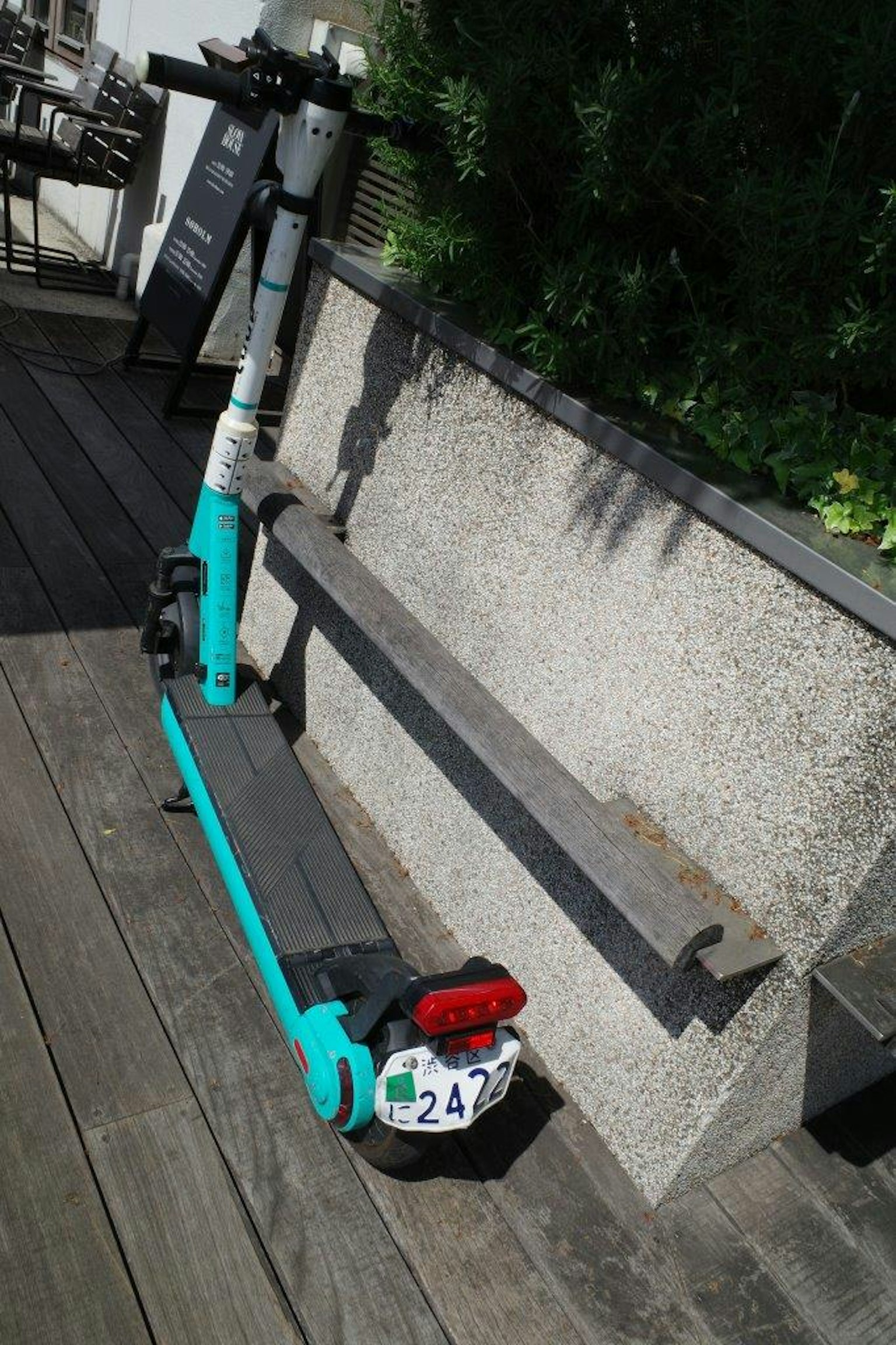 Un monopattino elettrico blu parcheggiato accanto a una panchina