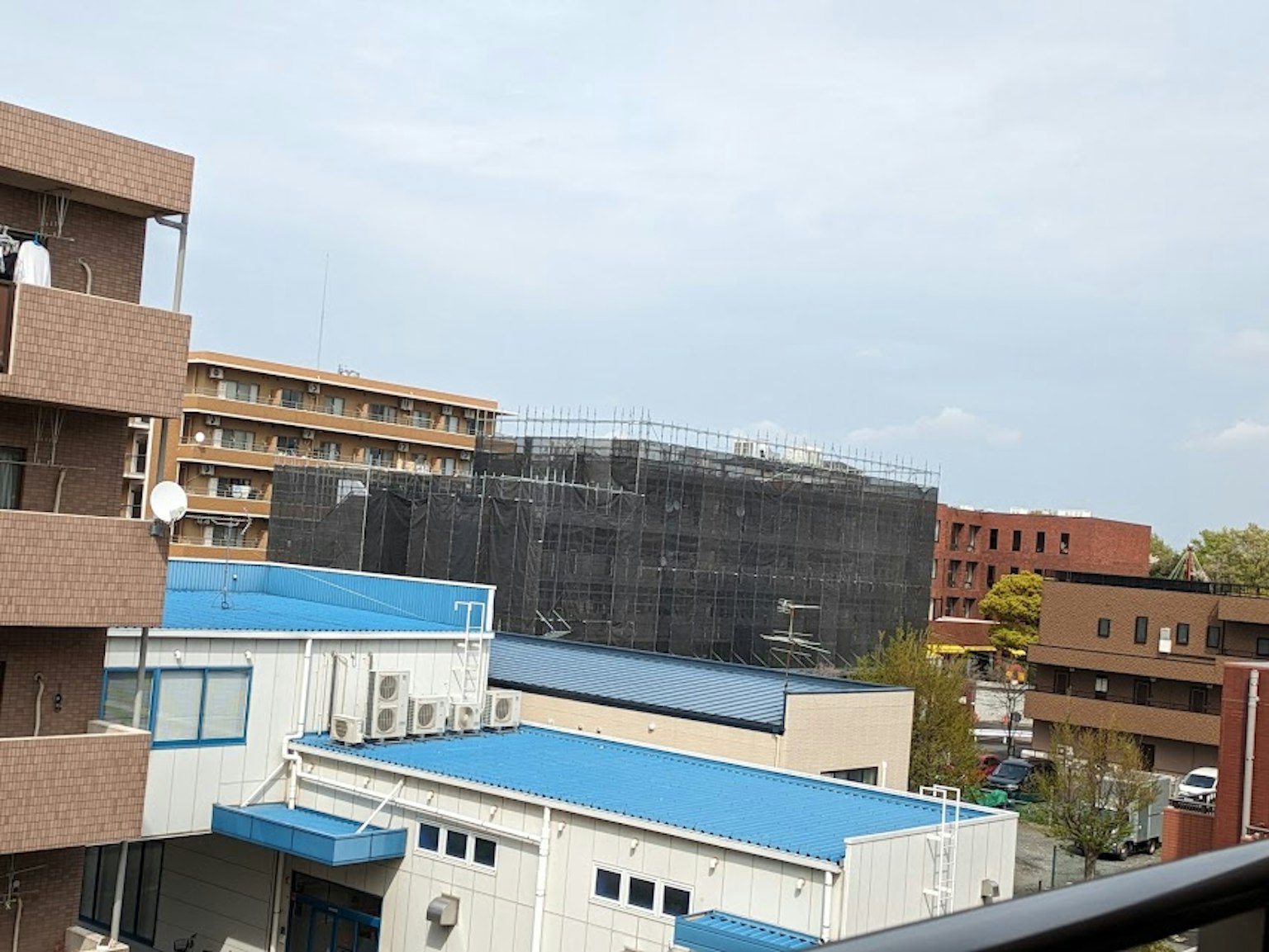建築工地的景觀黑色網罩建築藍色屋頂的結構和陰雲密布的天空