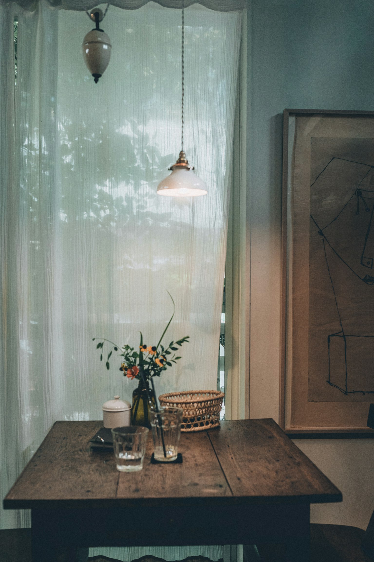 A well-lit table by the window featuring a vase of flowers and a coffee cup