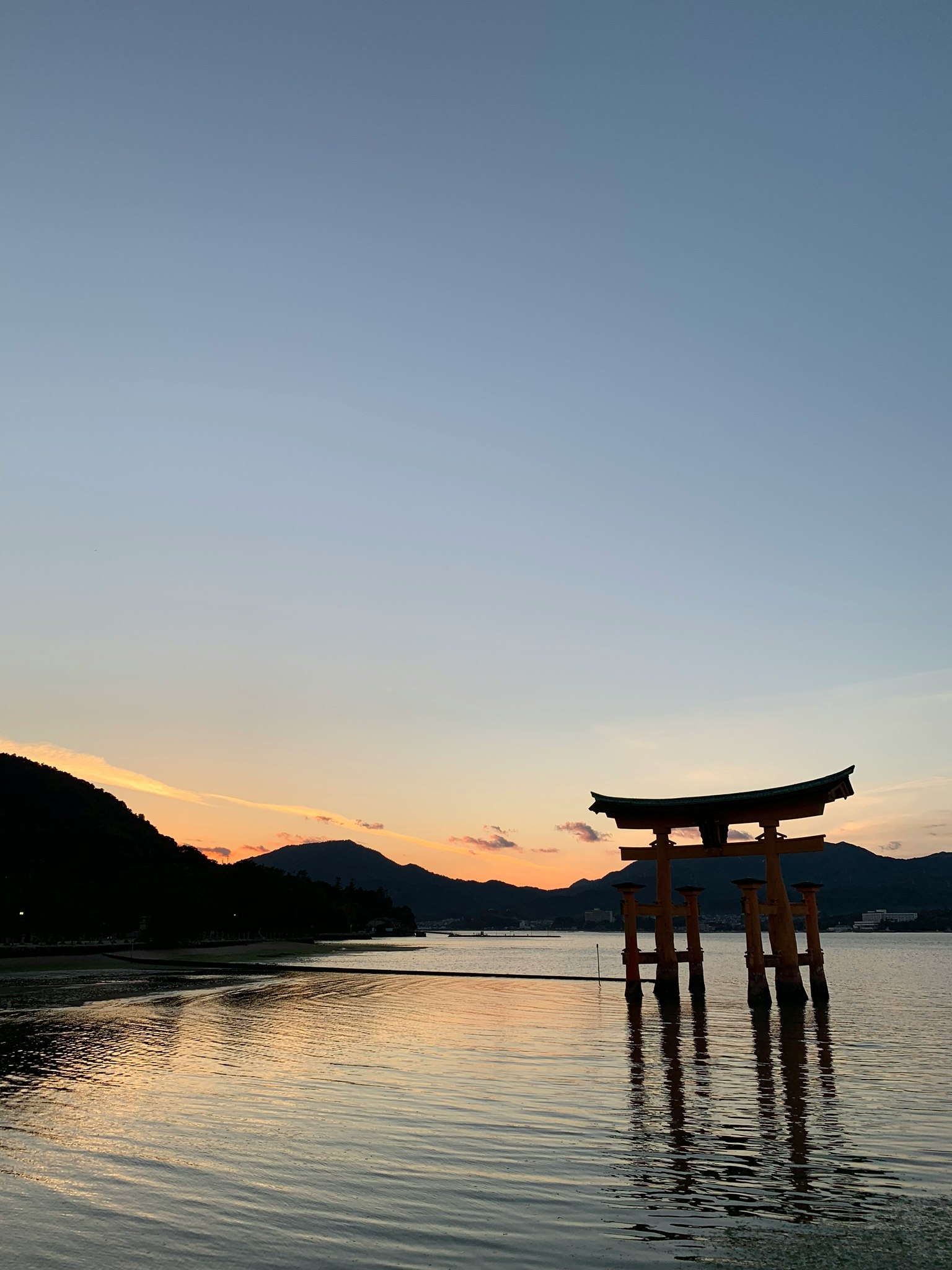 夕暮れの湖畔に立つ鳥居と水面の反射