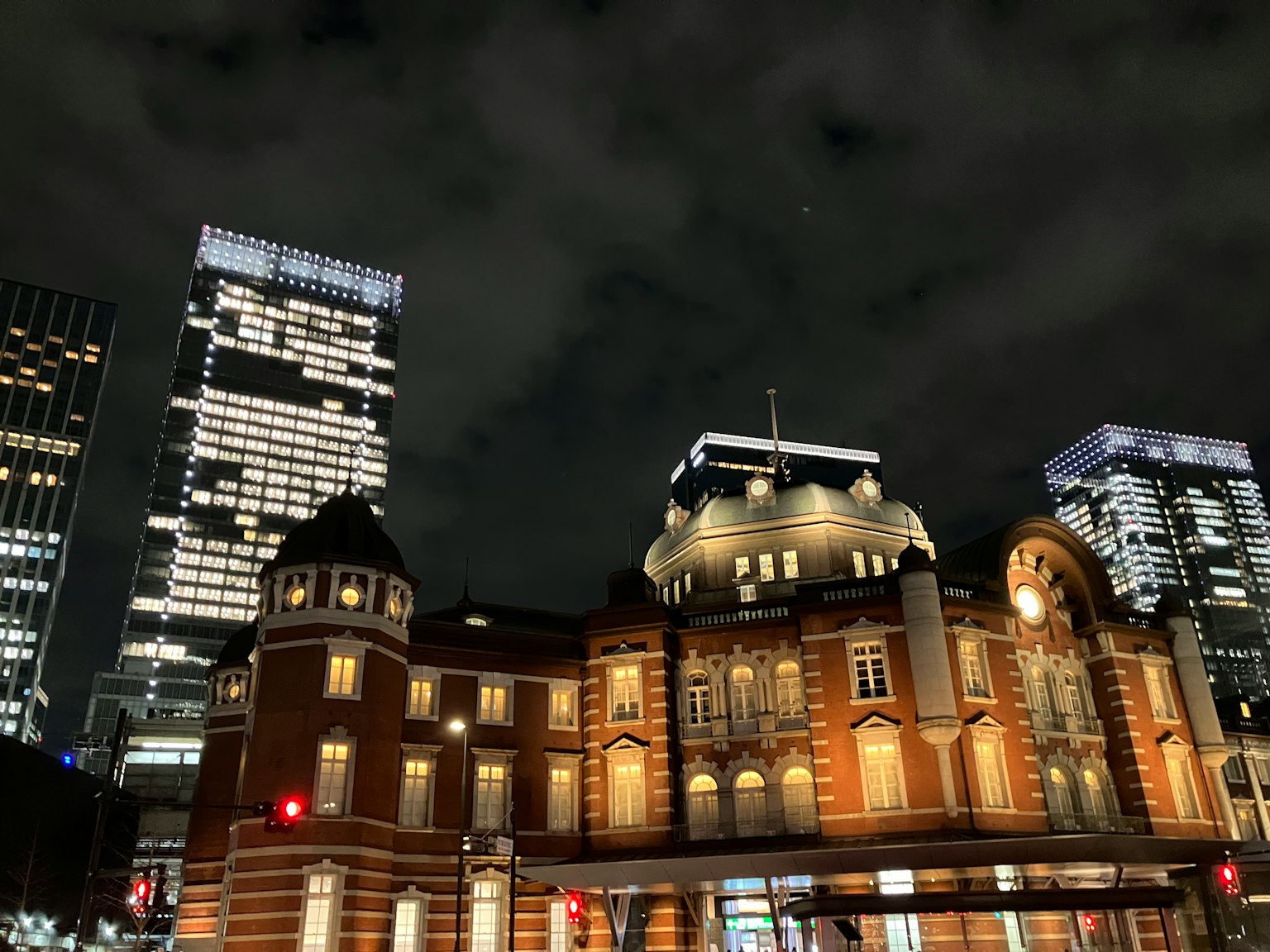 Vue nocturne de la gare de Tokyo avec une architecture historique éclairée et des gratte-ciels modernes