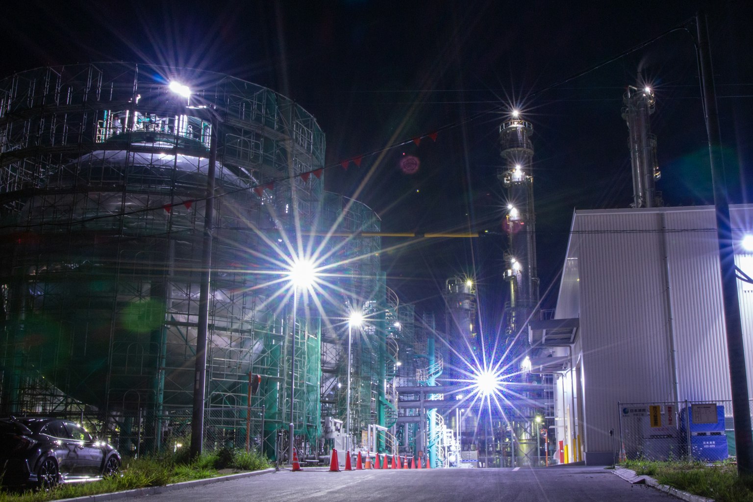 Nachtansicht einer Industrieanlage mit hellen Lichtern und Schornsteinen