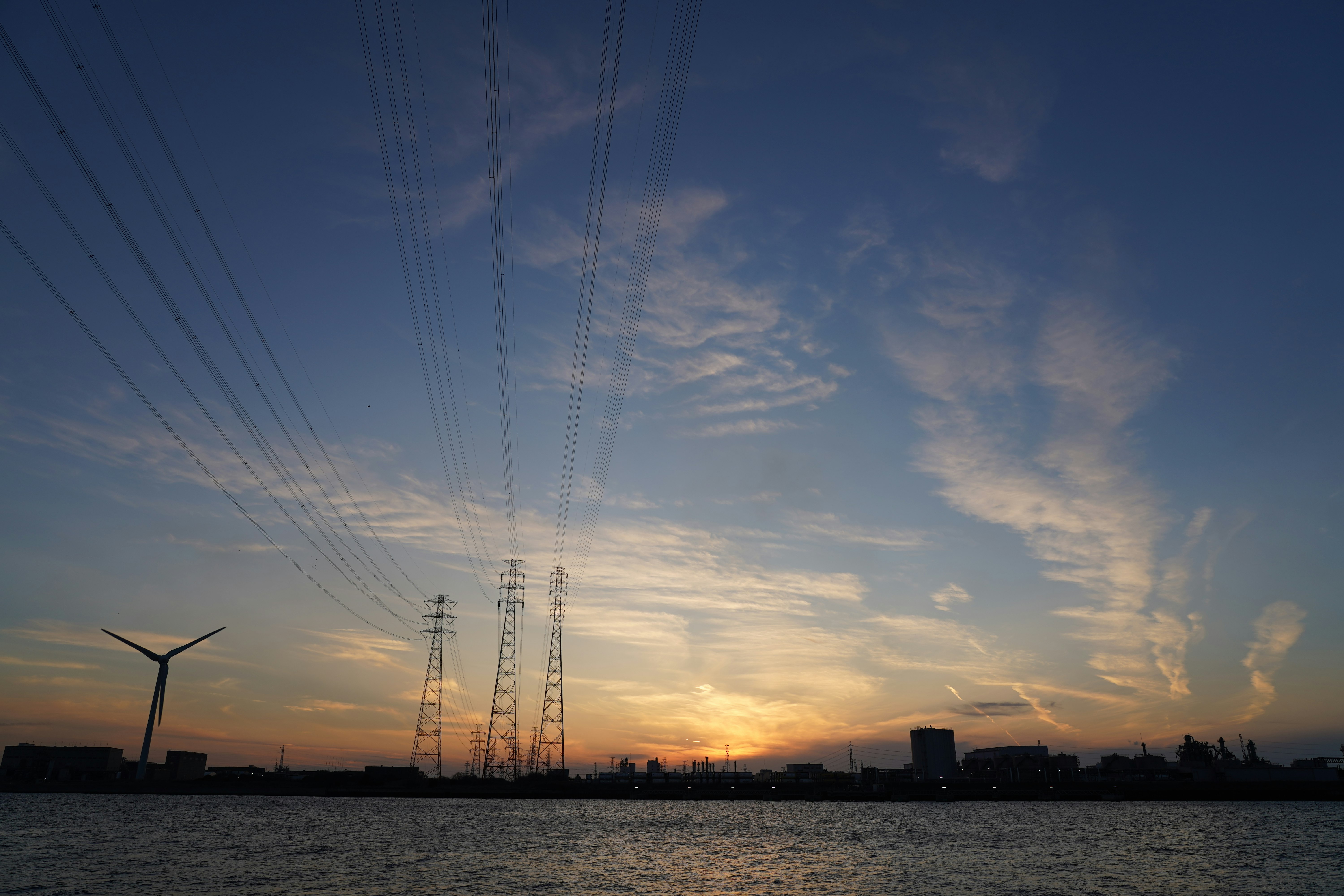 seaside sunset with wind turbines and power transmission towers
