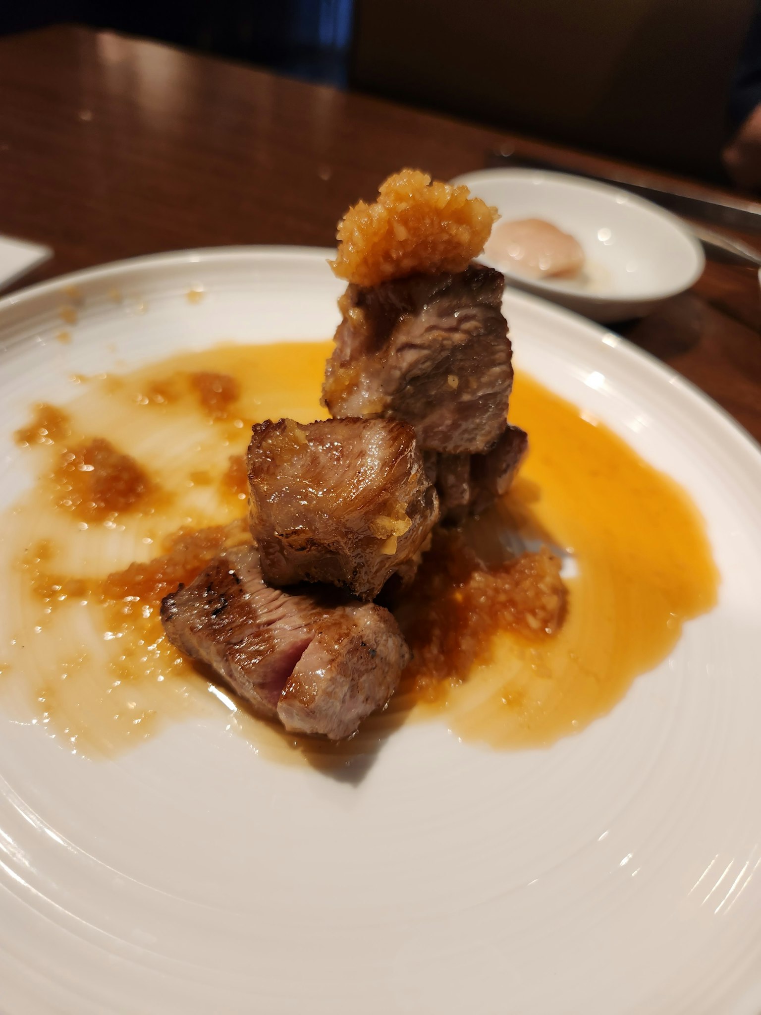 Pila di pezzi di carne alla griglia con salsa su un piatto bianco
