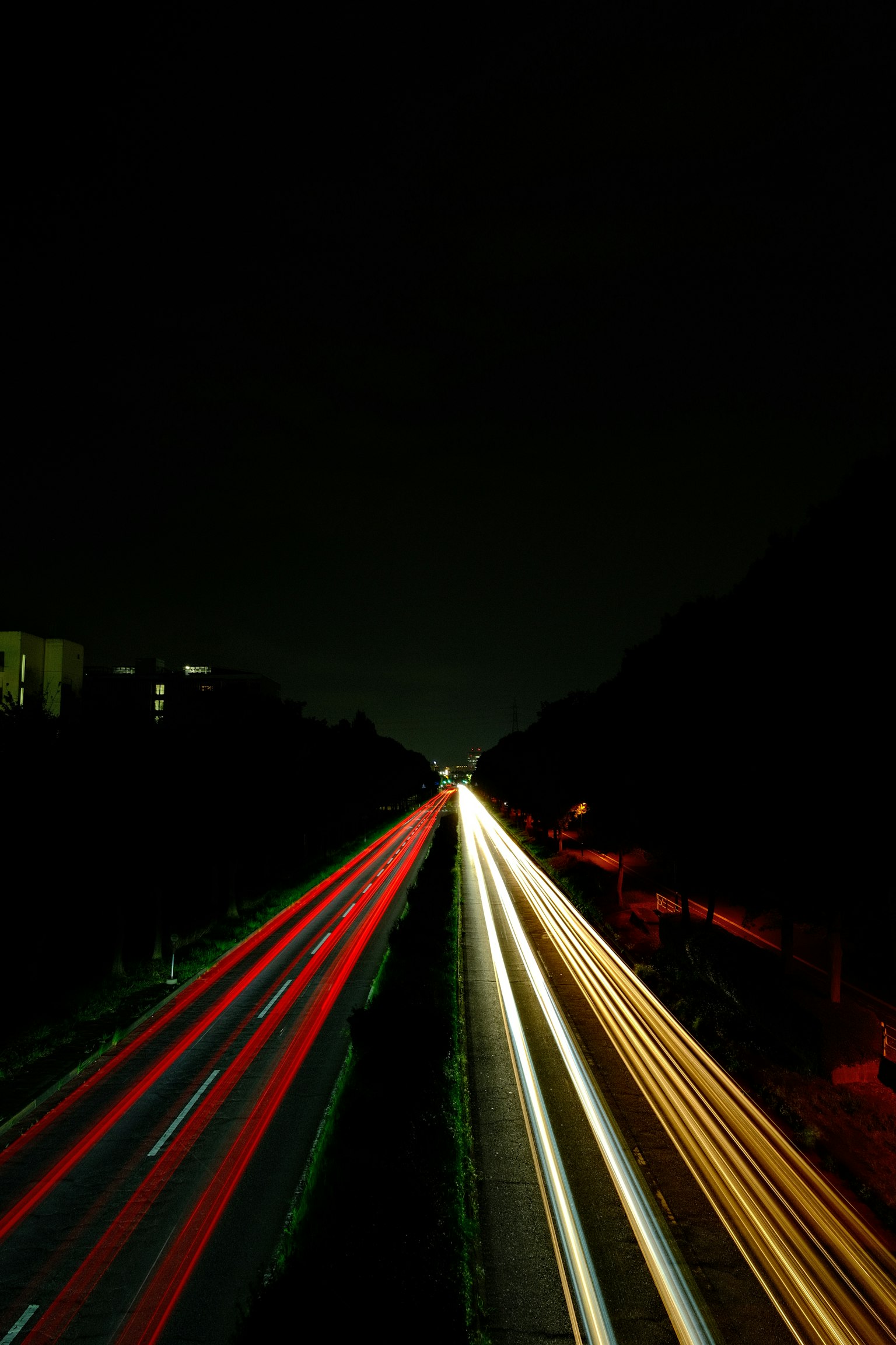 Langzeitbelichtung einer Autobahn bei Nacht mit roten und weißen Lichtspuren von Fahrzeugen