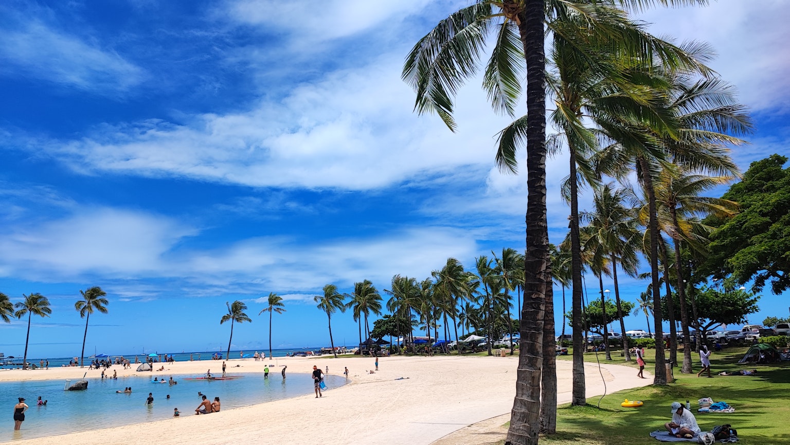 Beach scene with blue sky and white sand people enjoying the water