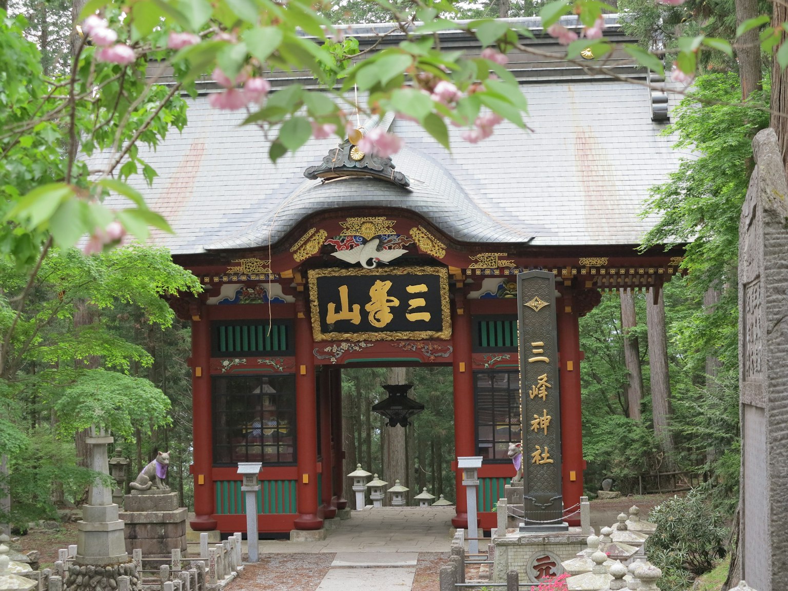 푸른 녹음으로 둘러싸인 전통 일본 사원 입구 다채로운 장식이 특징