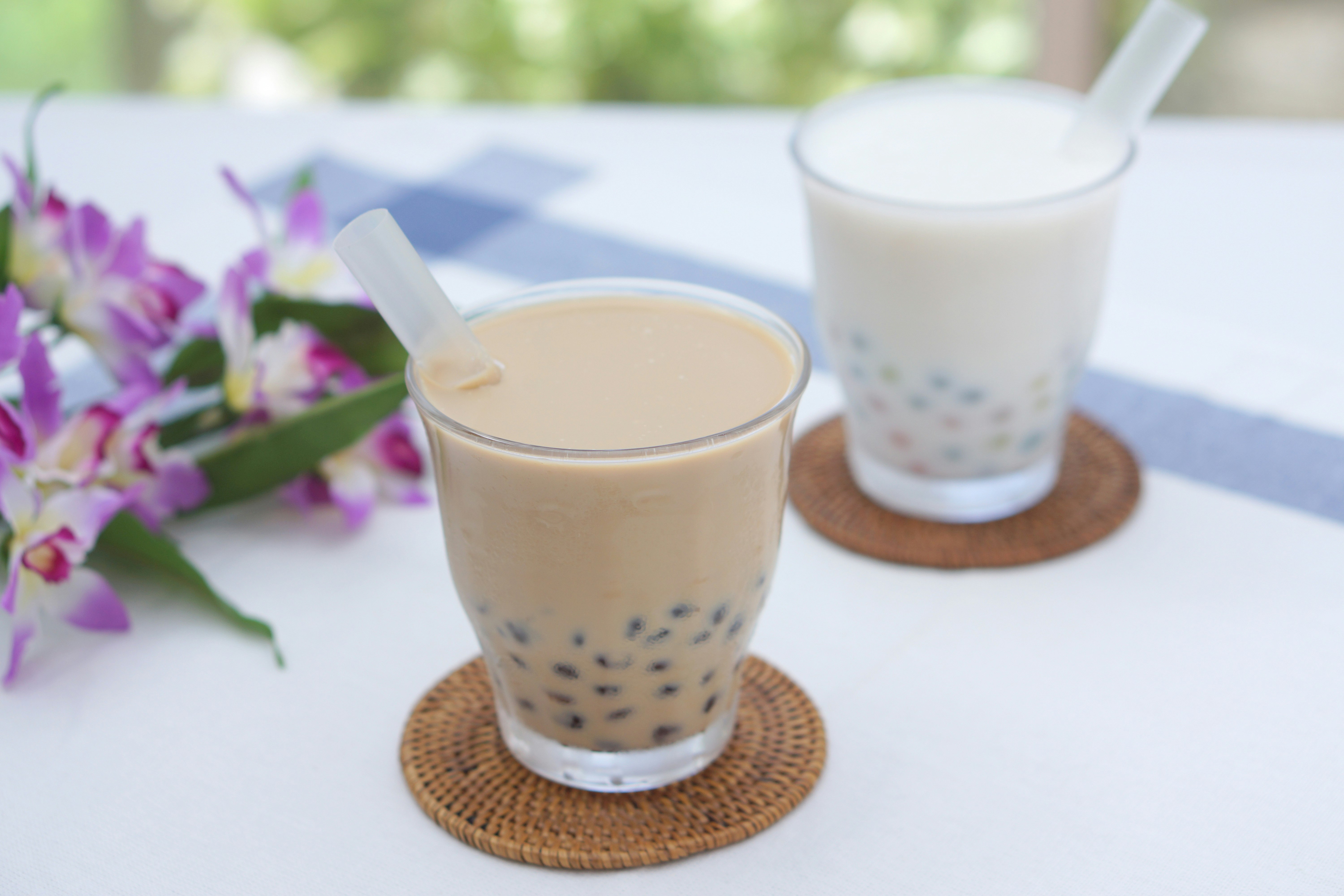 桌上摆放的两杯珍珠奶茶和花束