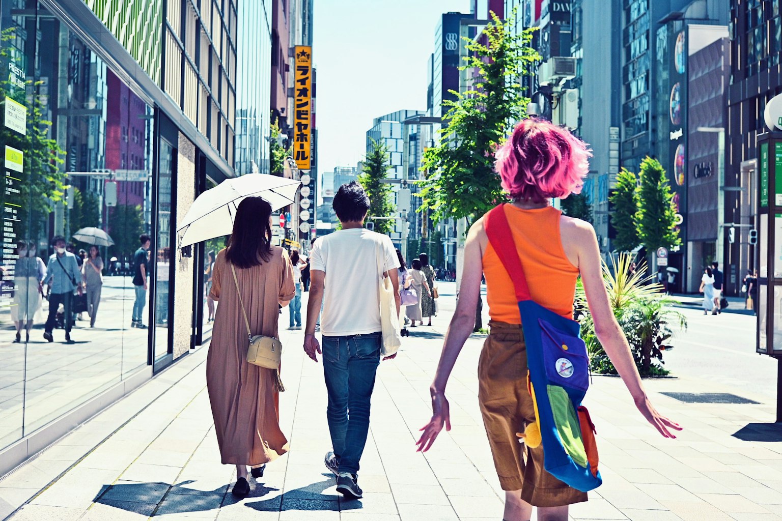 ผู้หญิงที่มีผมสีสันเดินอยู่ในเมืองพร้อมกับคนสองคนข้างหน้า