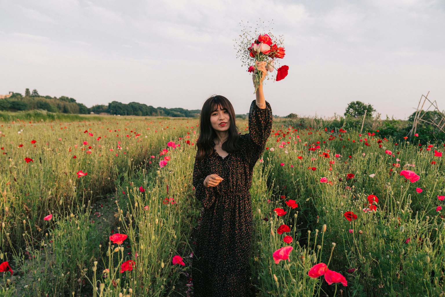 Una donna che tiene un mazzo di fiori in un campo di fiori rossi