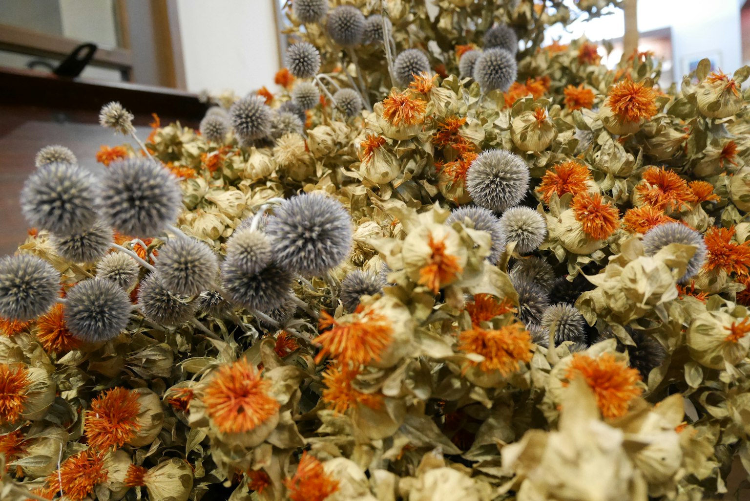 Un arrangiamento di fiori secchi con elementi arancioni e grigi