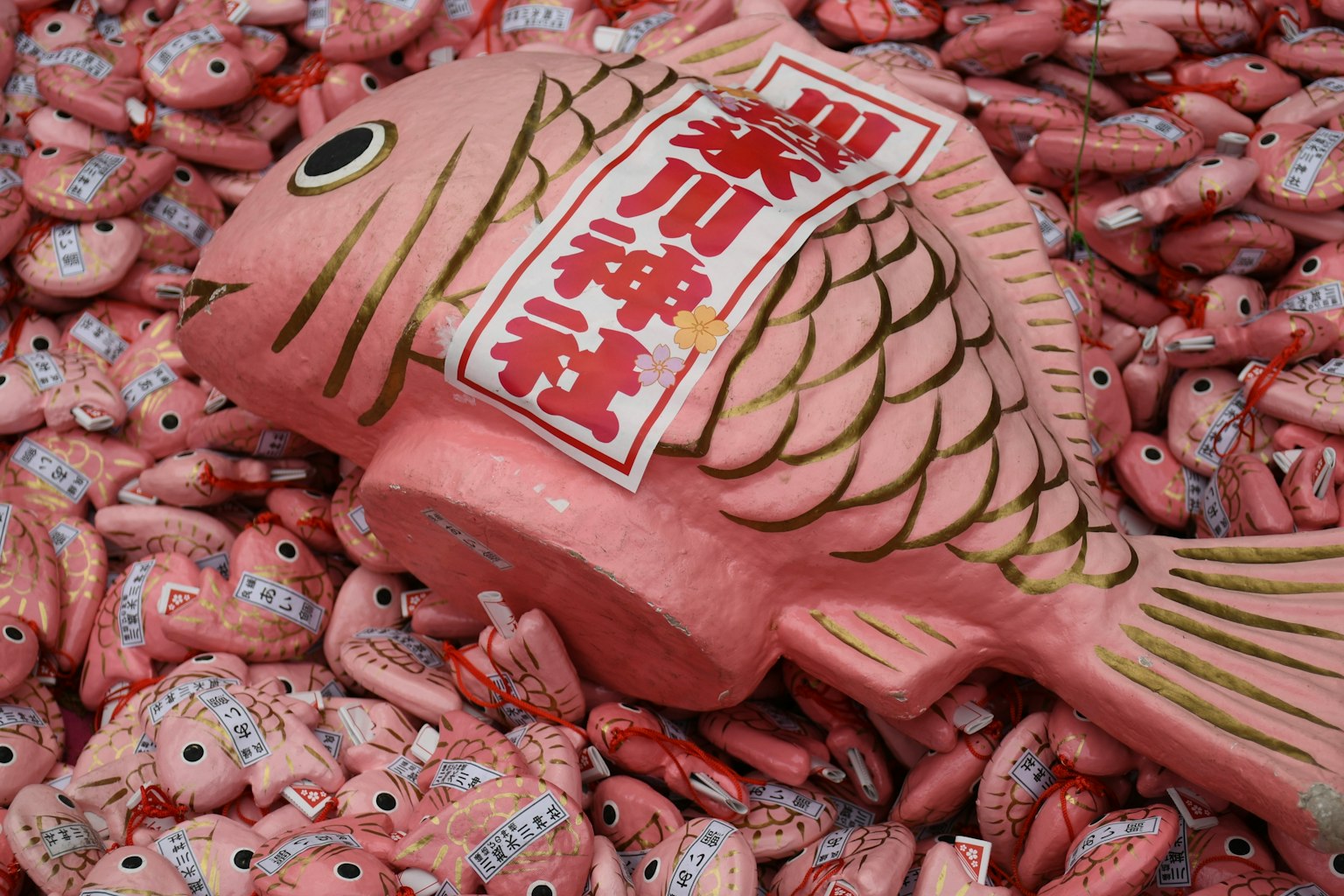 A large pink fish sculpture surrounded by smaller pink fish