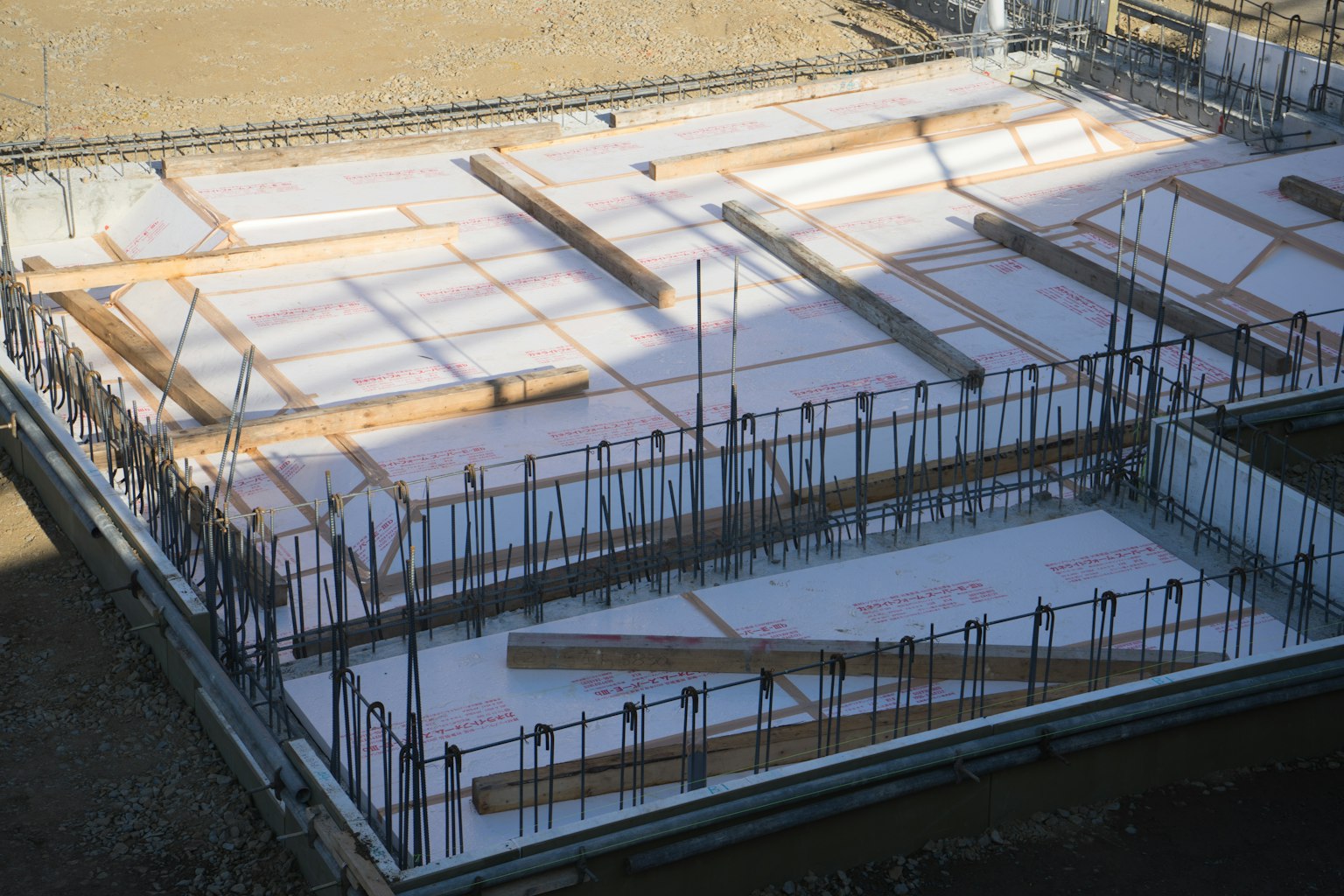 Fondation en béton sur un chantier avec des poutres en bois et des barres d'armature disposées