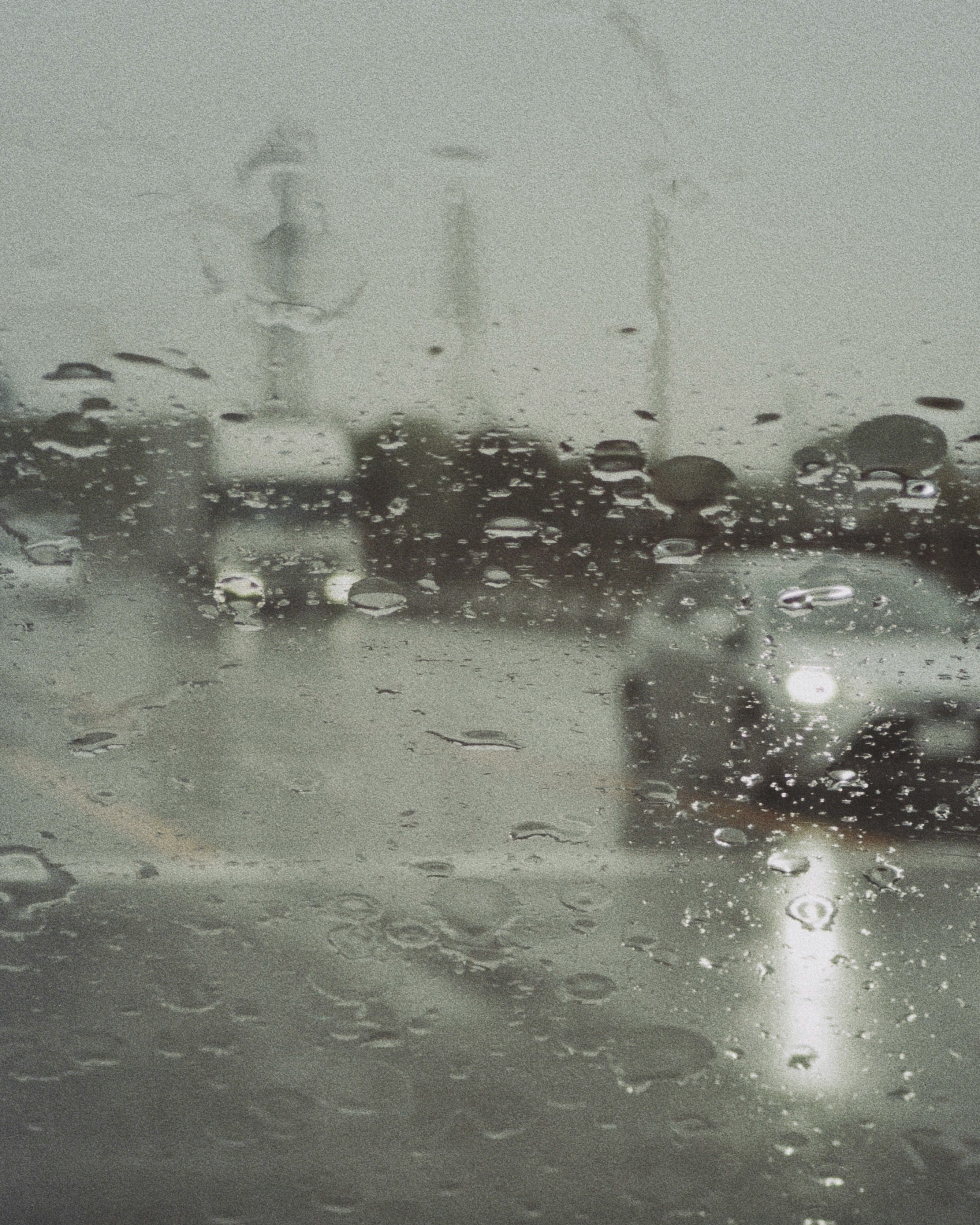 雨粒のついた窓越しに見える街の車と信号