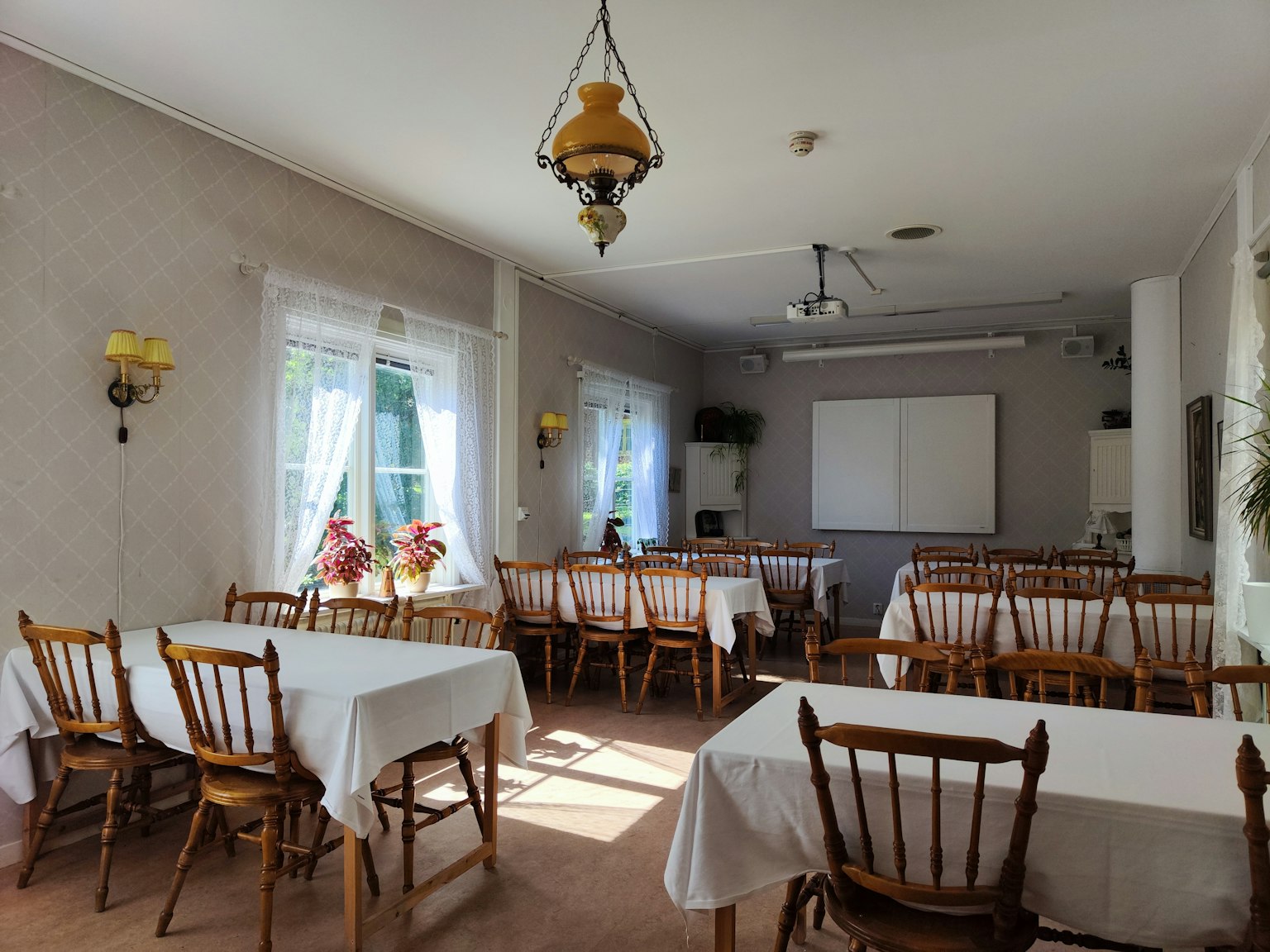 Sala de reuniones brillante con mesas blancas y sillas de madera dispuestas
