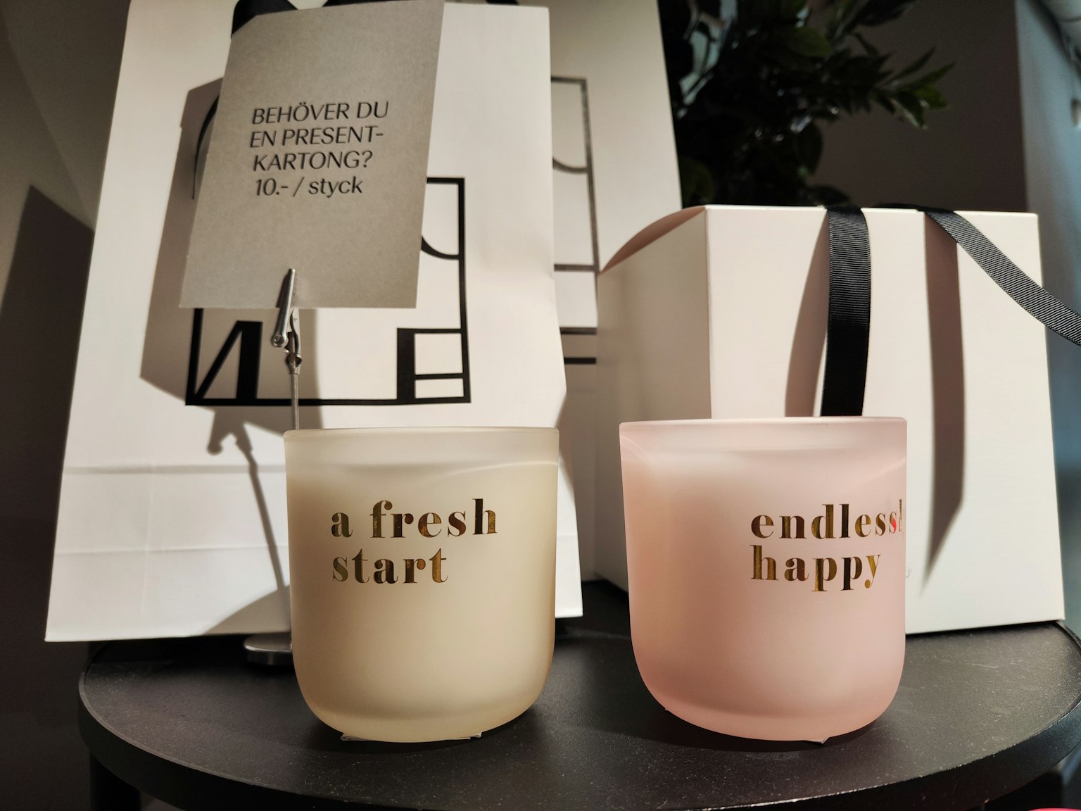 Hai ngọn nến có nhãn a fresh start và endless happy trên bàn cùng một hộp quà trong không gian hiện đại