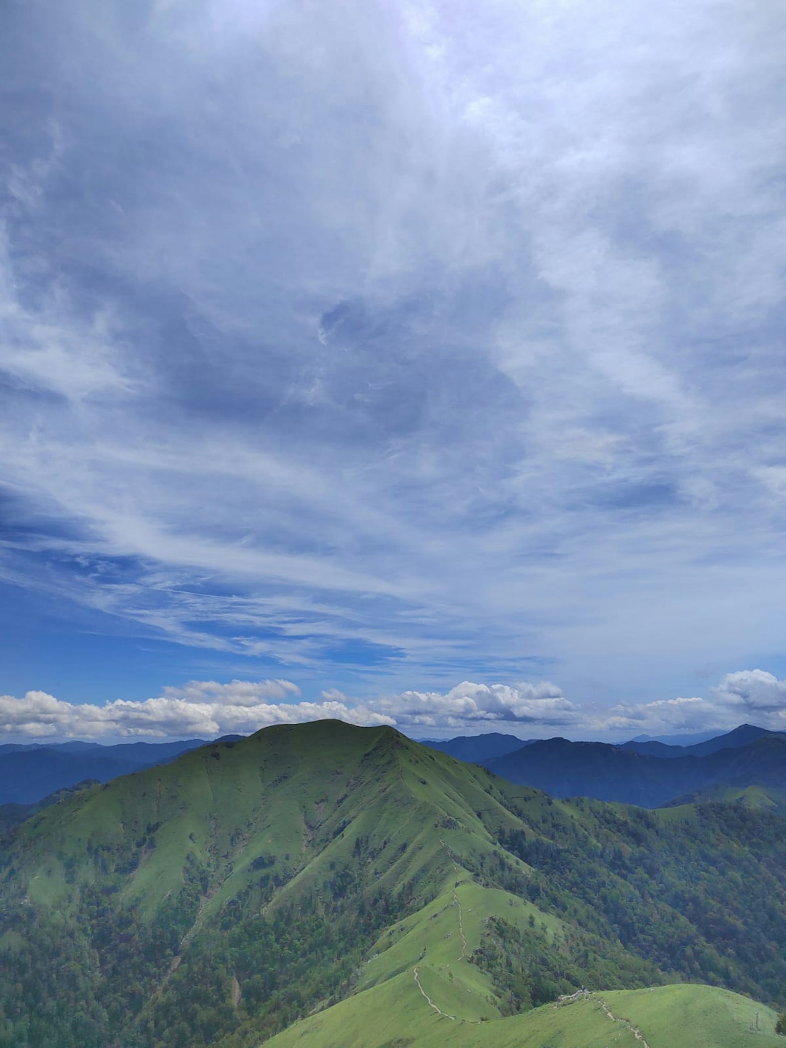 Gunung hijau subur di bawah langit biru