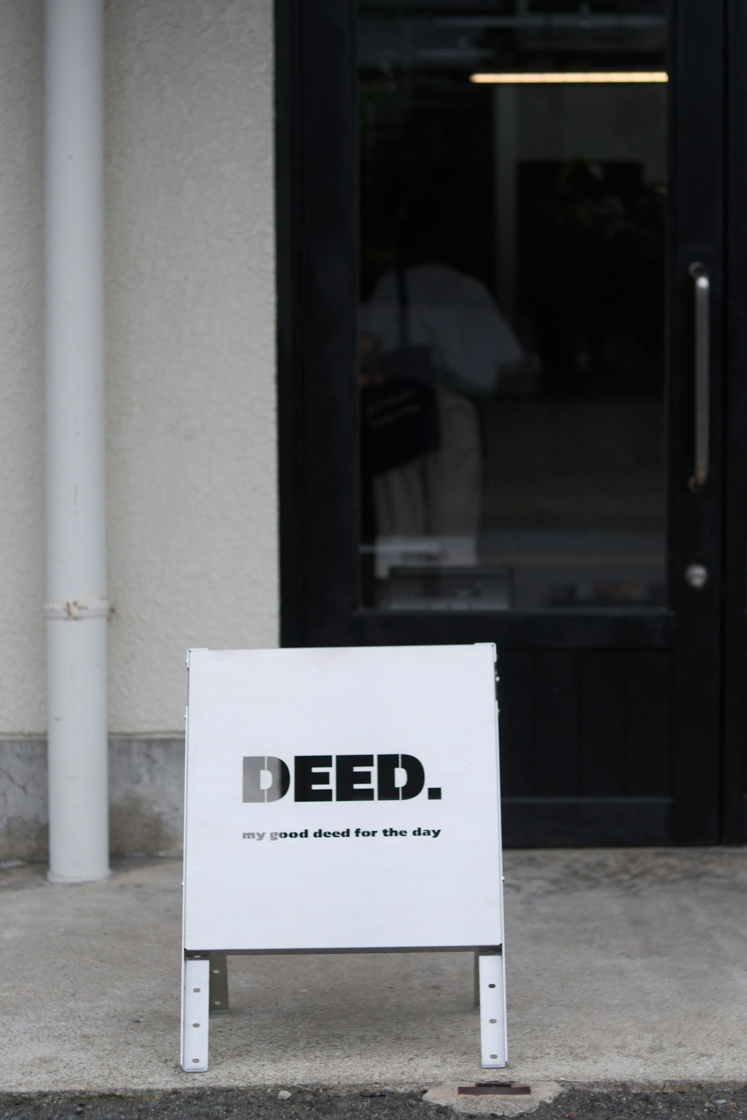 상점 입구 앞에 있는 DEED라는 검은 글씨가 적힌 흰색 간판
