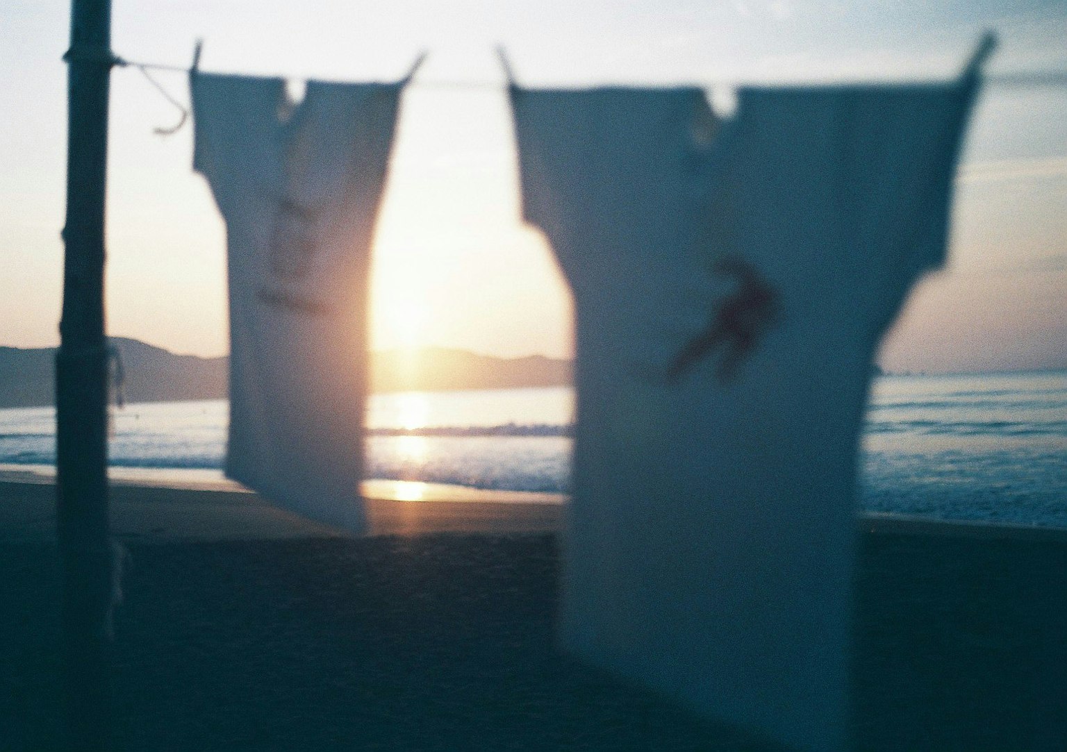 Chemises blanches accrochées à une corde sur la plage avec un coucher de soleil en arrière-plan