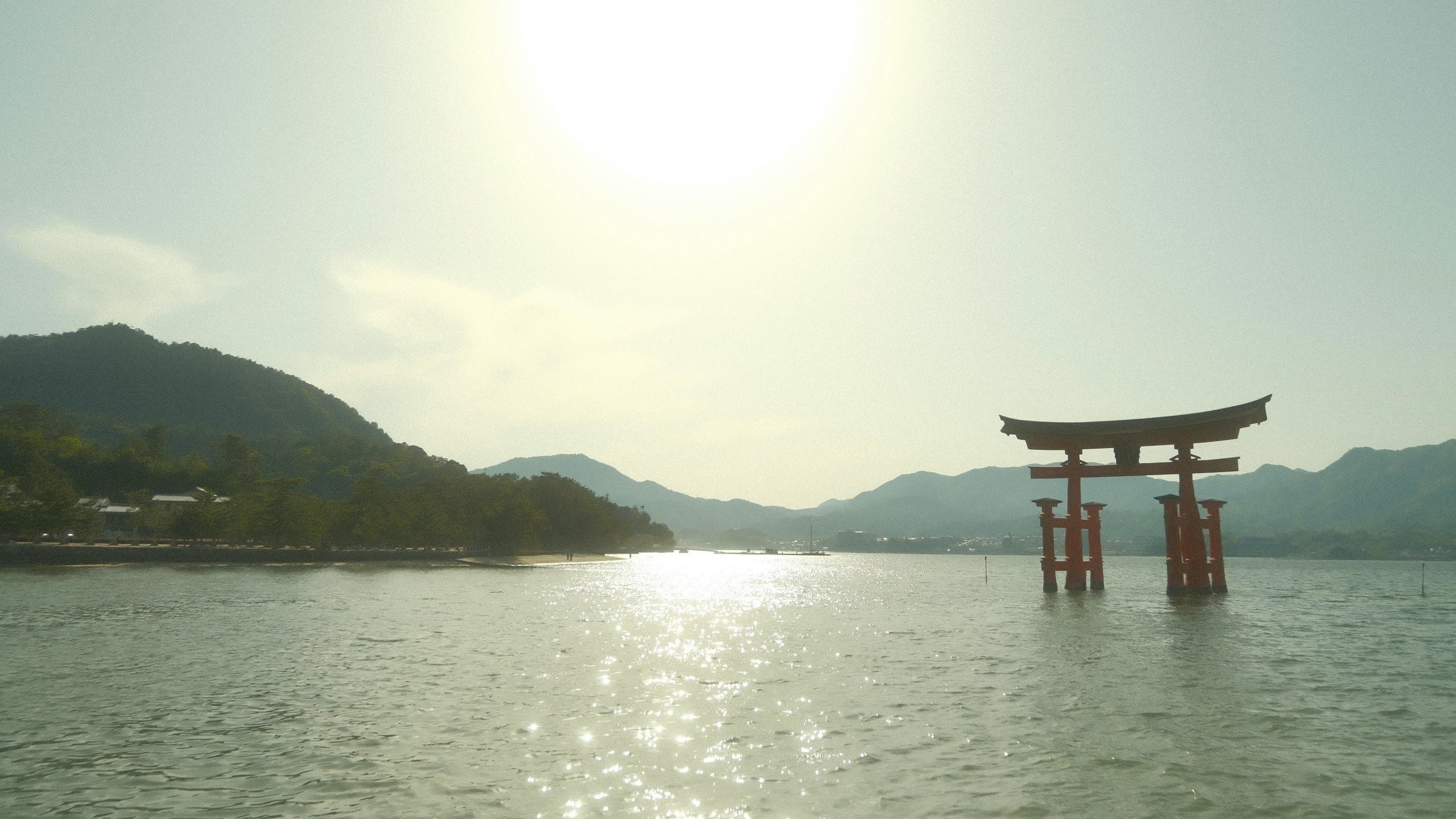 海に浮かぶ鳥居と夕日が反射する水面と山並み