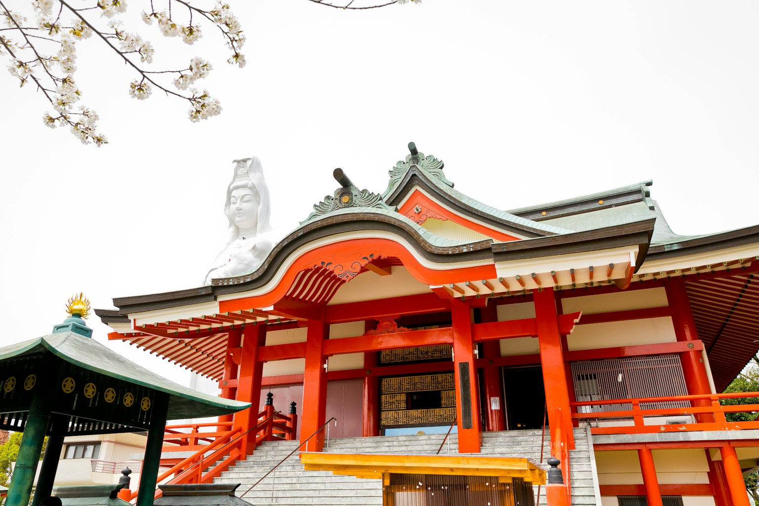 Templo japonés tradicional con techo rojo y cerezos en flor