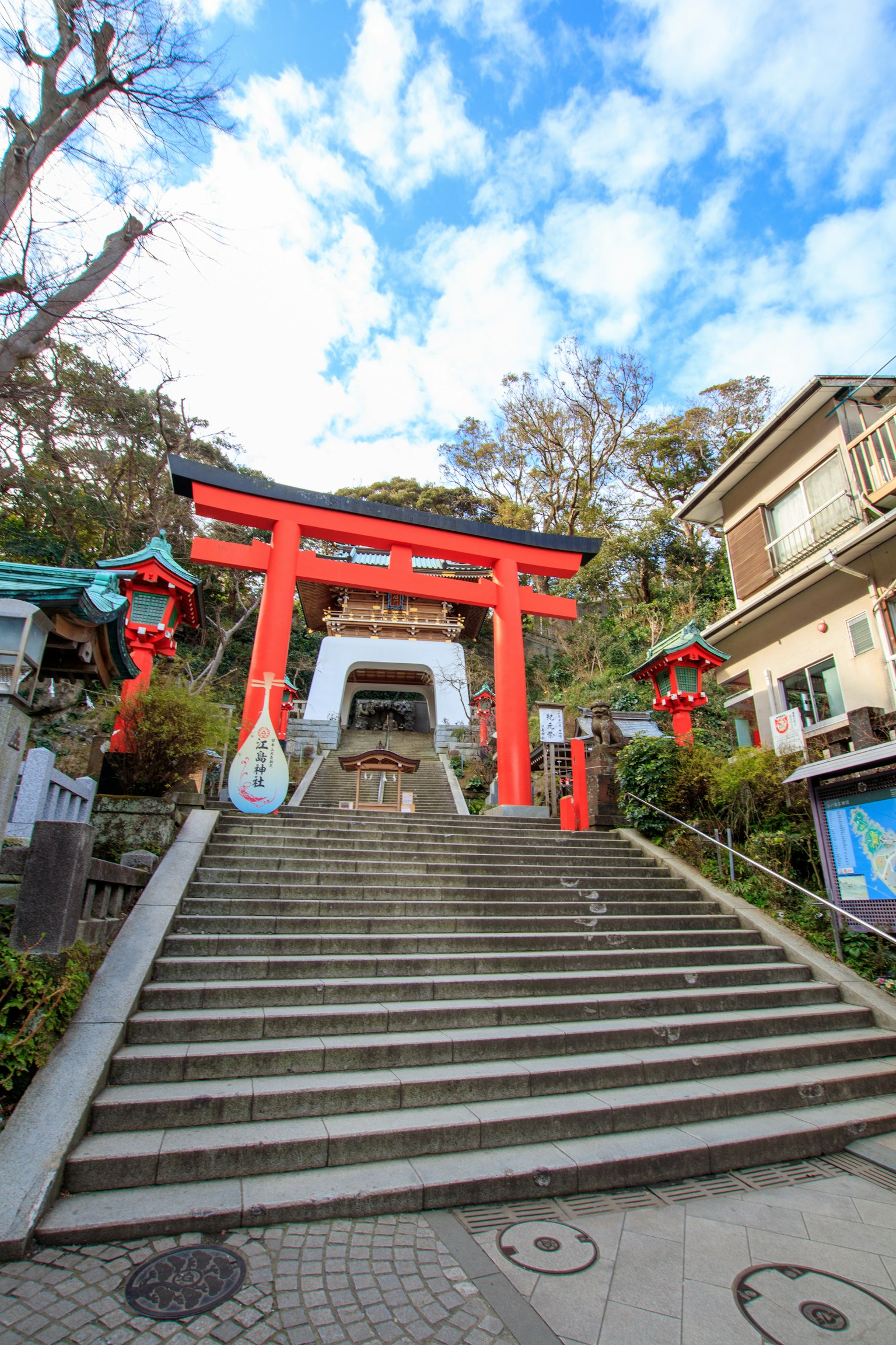 Red torii gate and steps leading to a shrine under a blue sky
