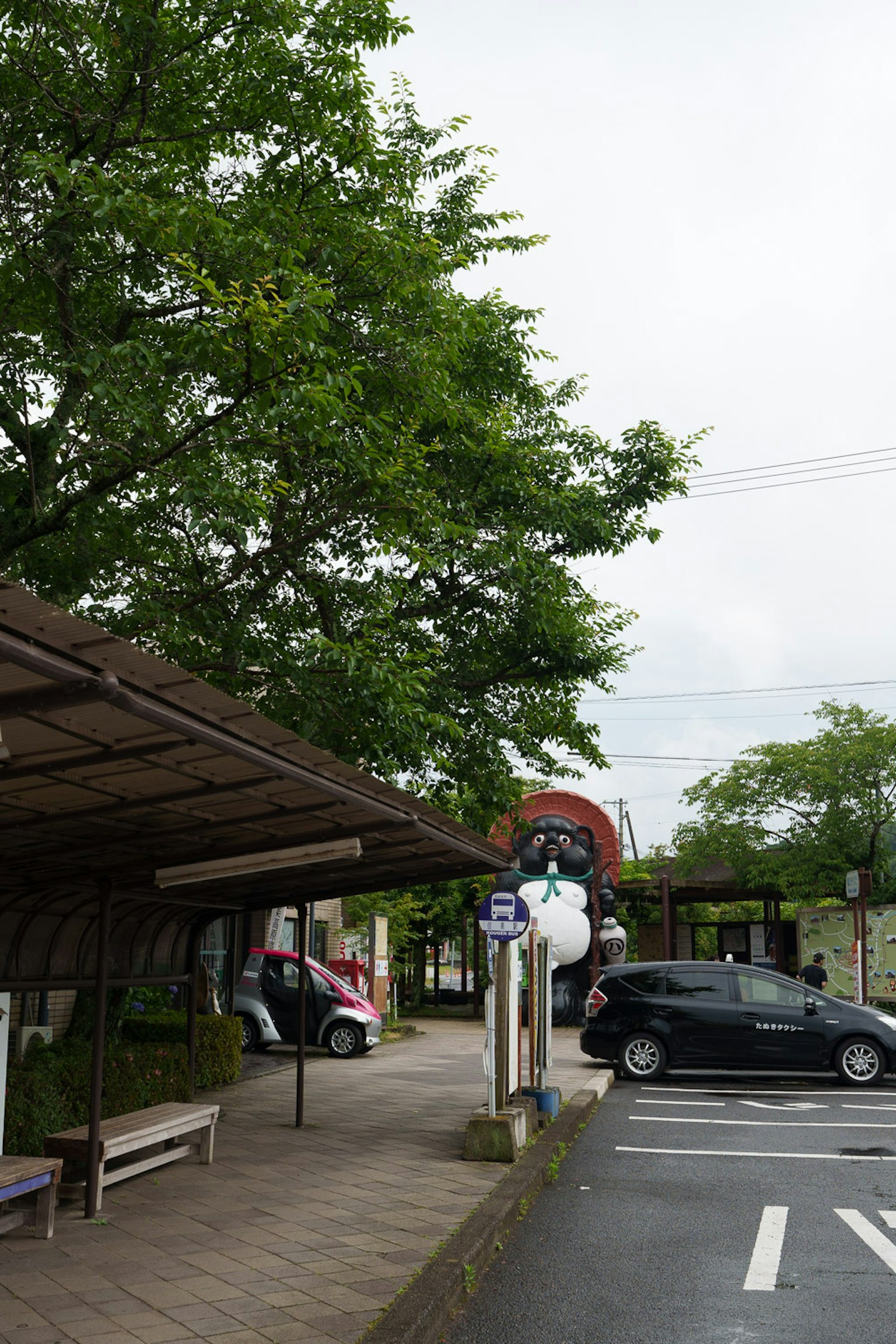 Vista escénica de una parada de autobús con árboles verdes y coches estacionados