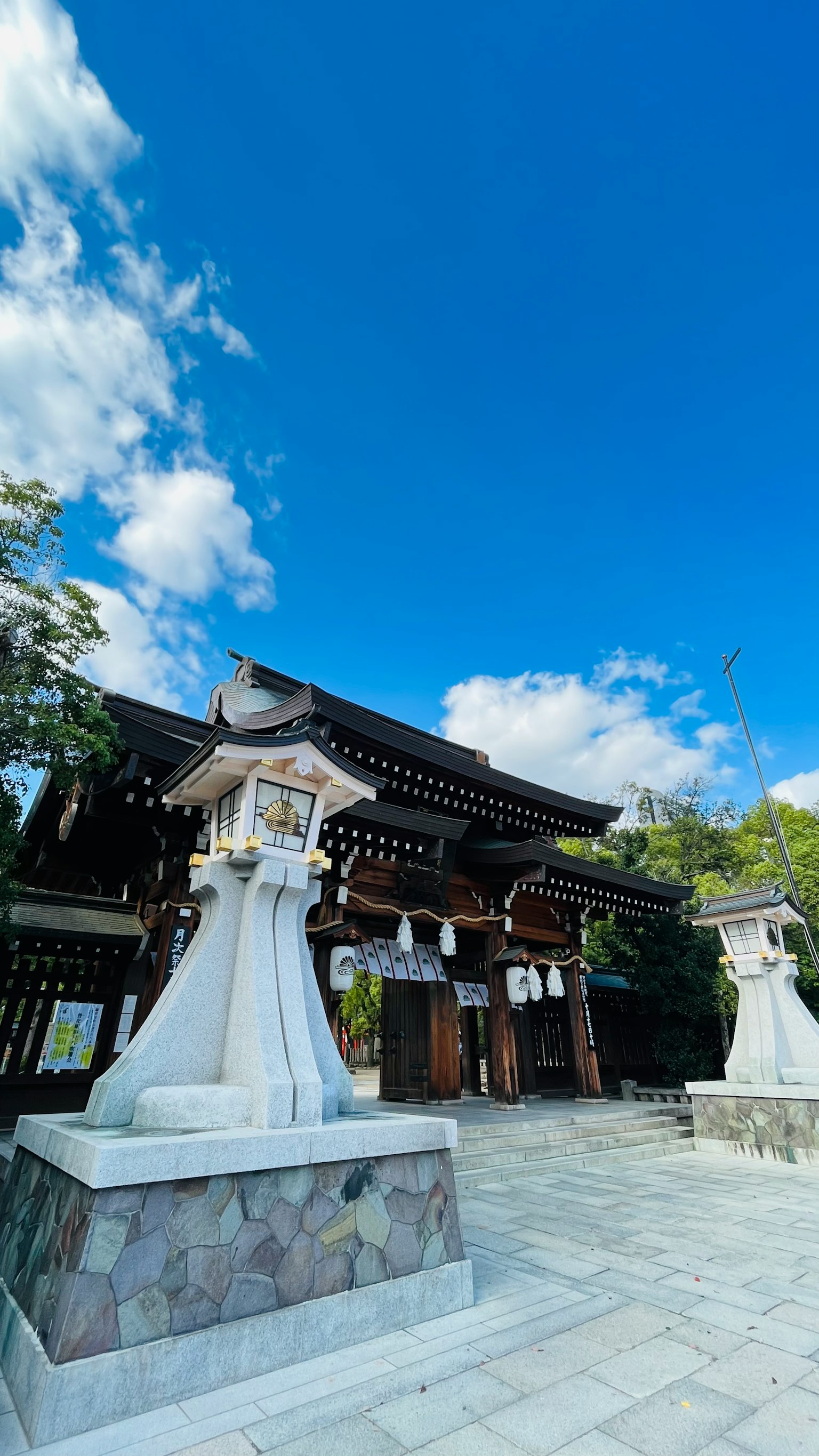 Eingang zu einem traditionellen japanischen Schrein mit Ste lanternen unter einem blauen Himmel